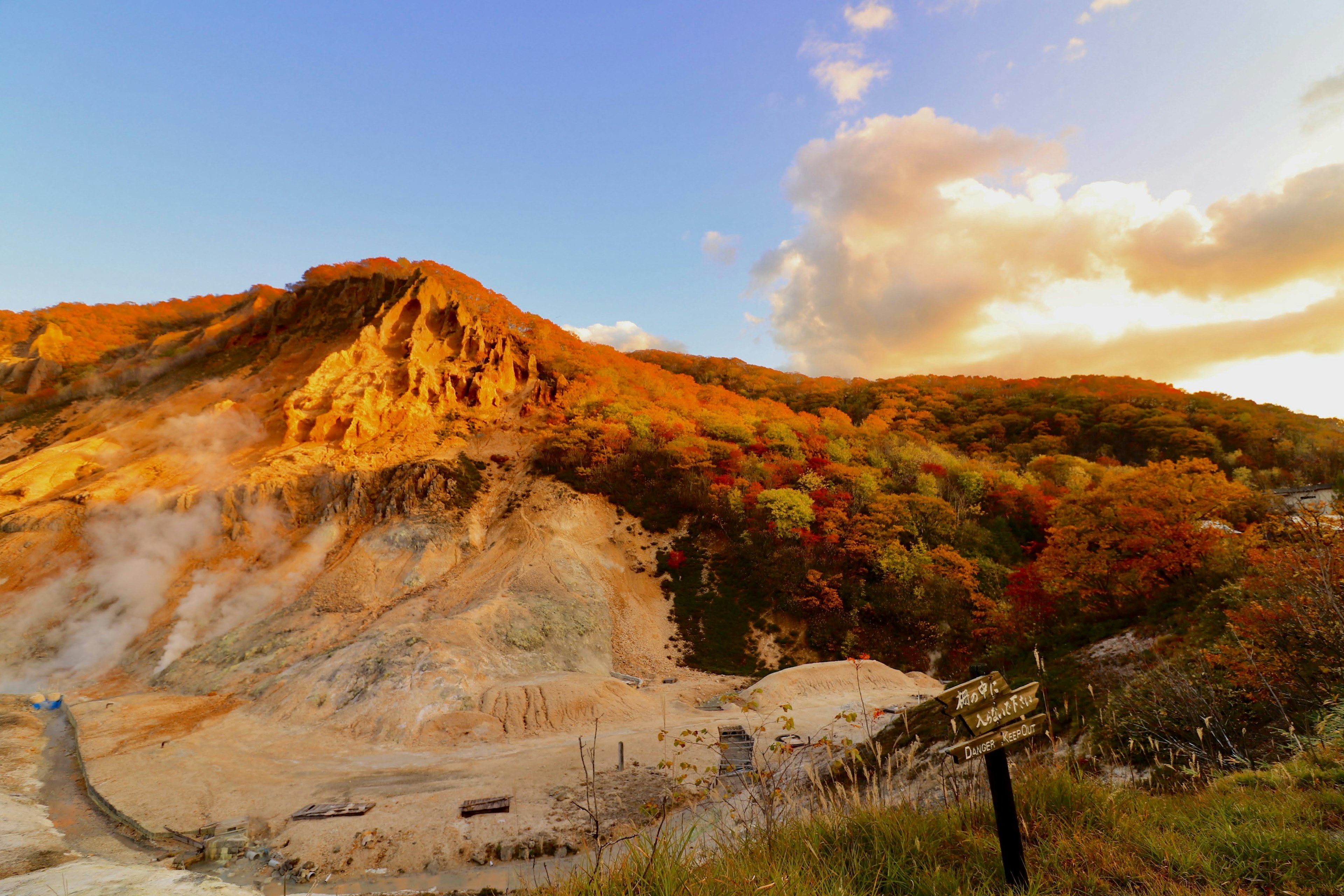 Paisaje montañoso iluminado por el atardecer con follaje de otoño