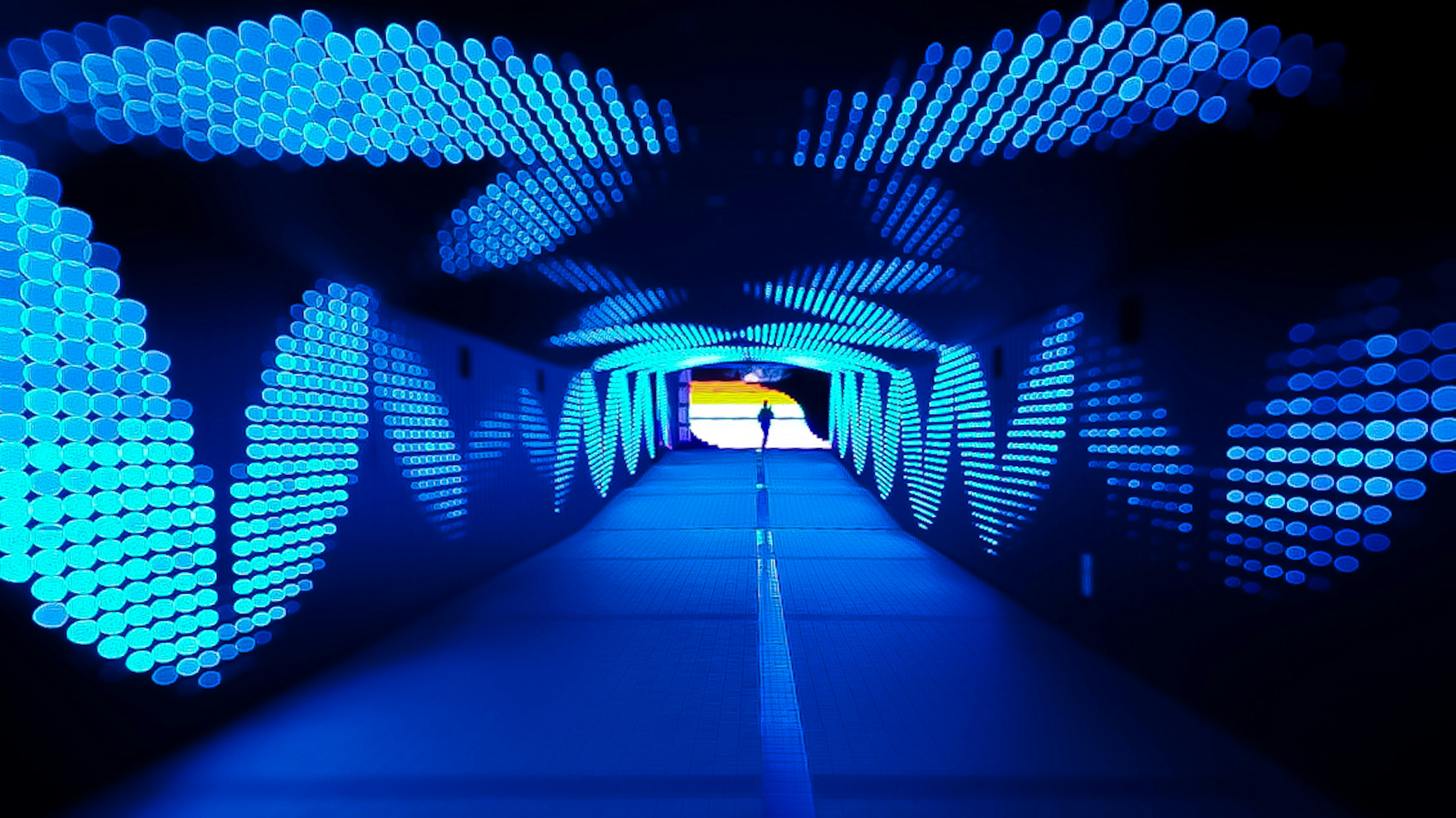 Un tunnel illuminato da luci blu con la silhouette di una persona