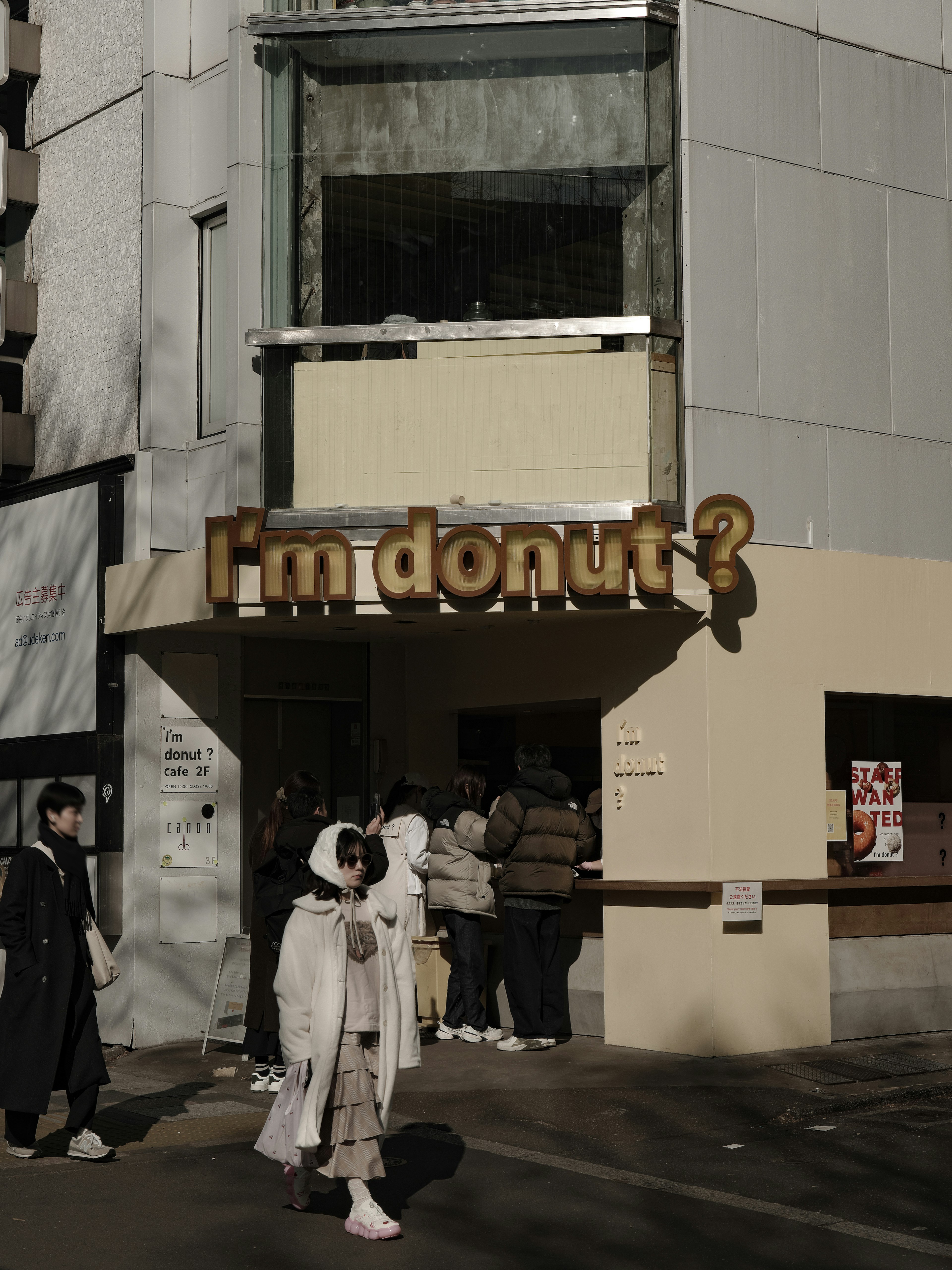 Donut shop with a prominent sign and people in front