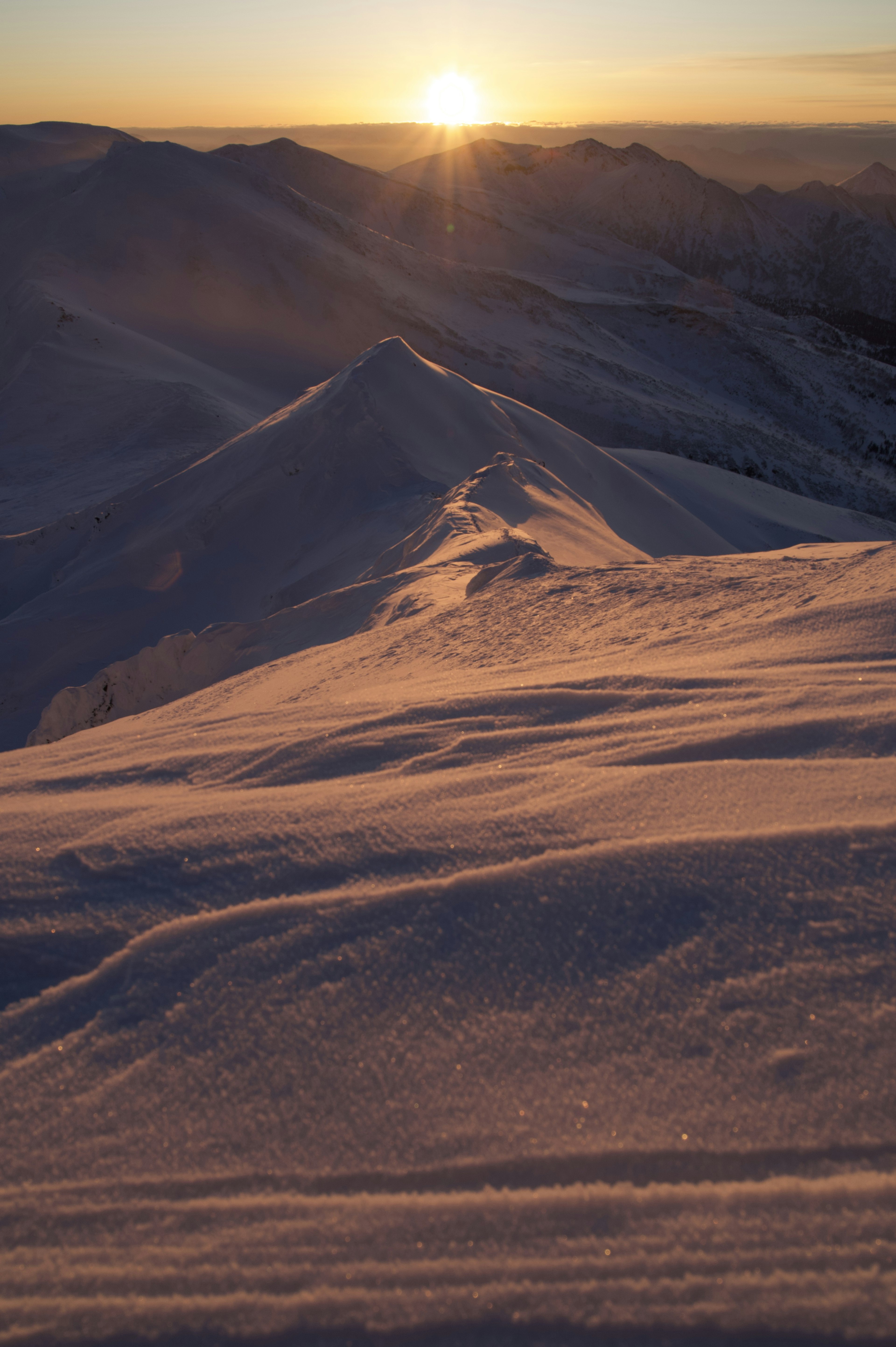 Amanecer sobre montañas cubiertas de nieve con suaves pendientes