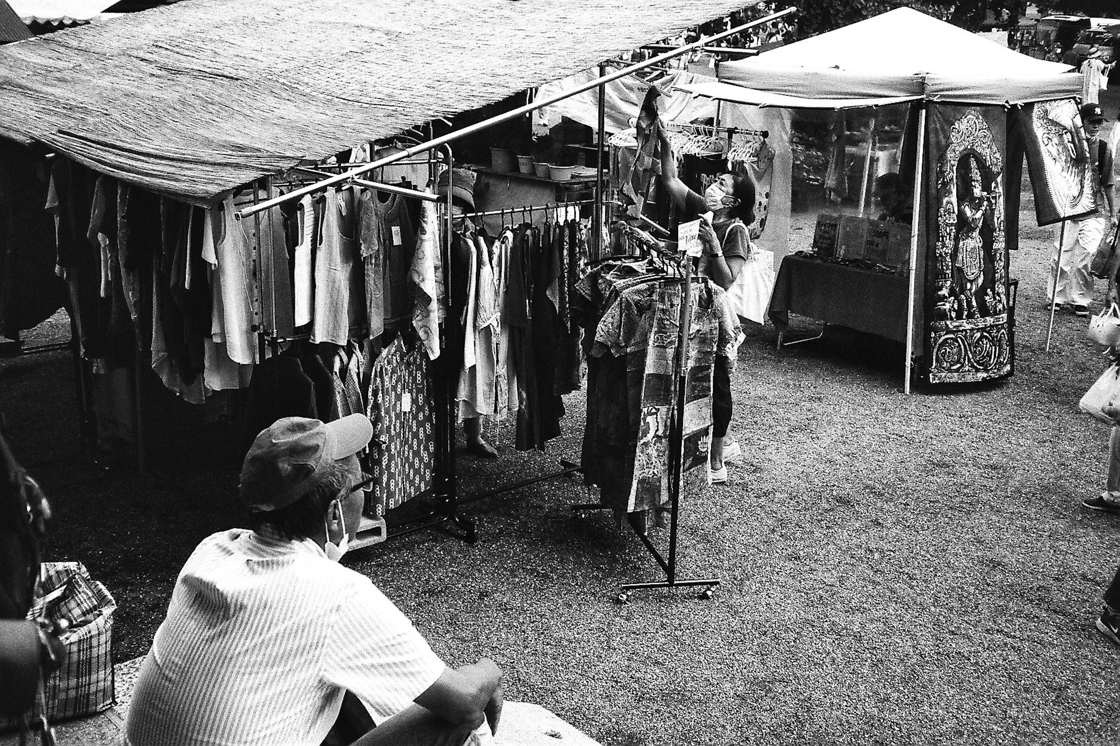 Scène de marché en noir et blanc avec des stands de vêtements et des personnes