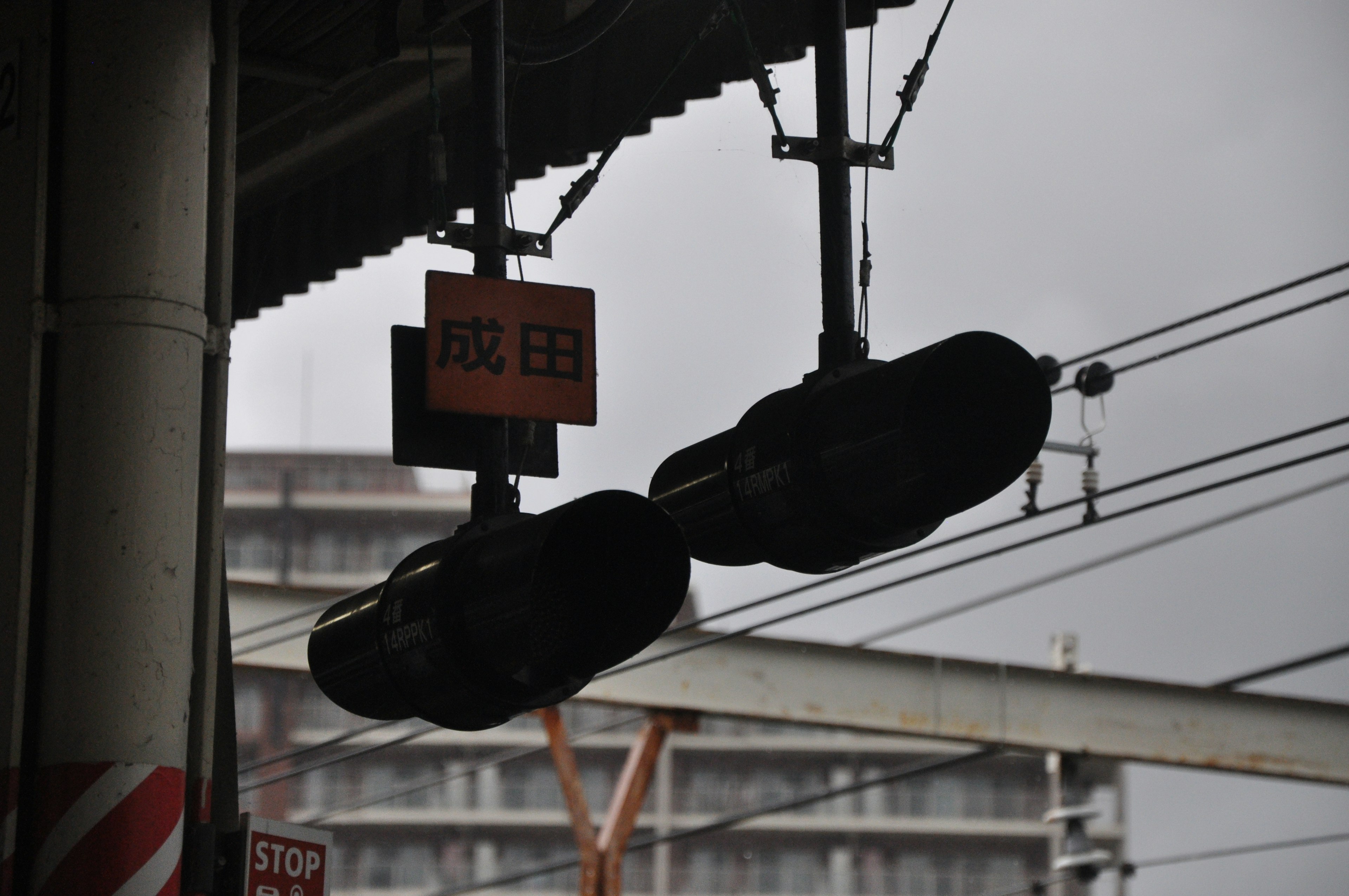 電車の信号機が暗い雲の下に見える駅の風景