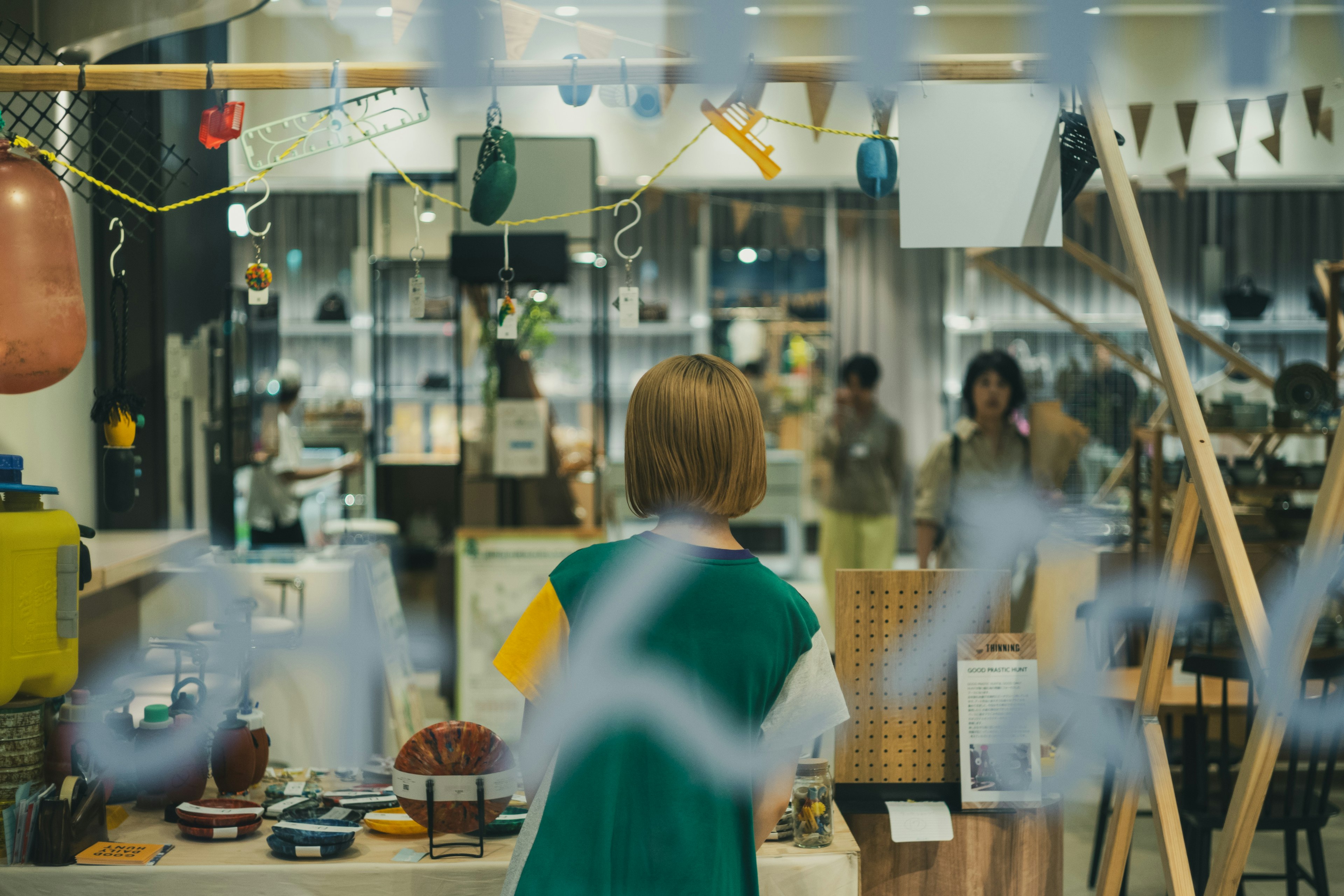 A woman viewed from behind looking at various items in a store through glass