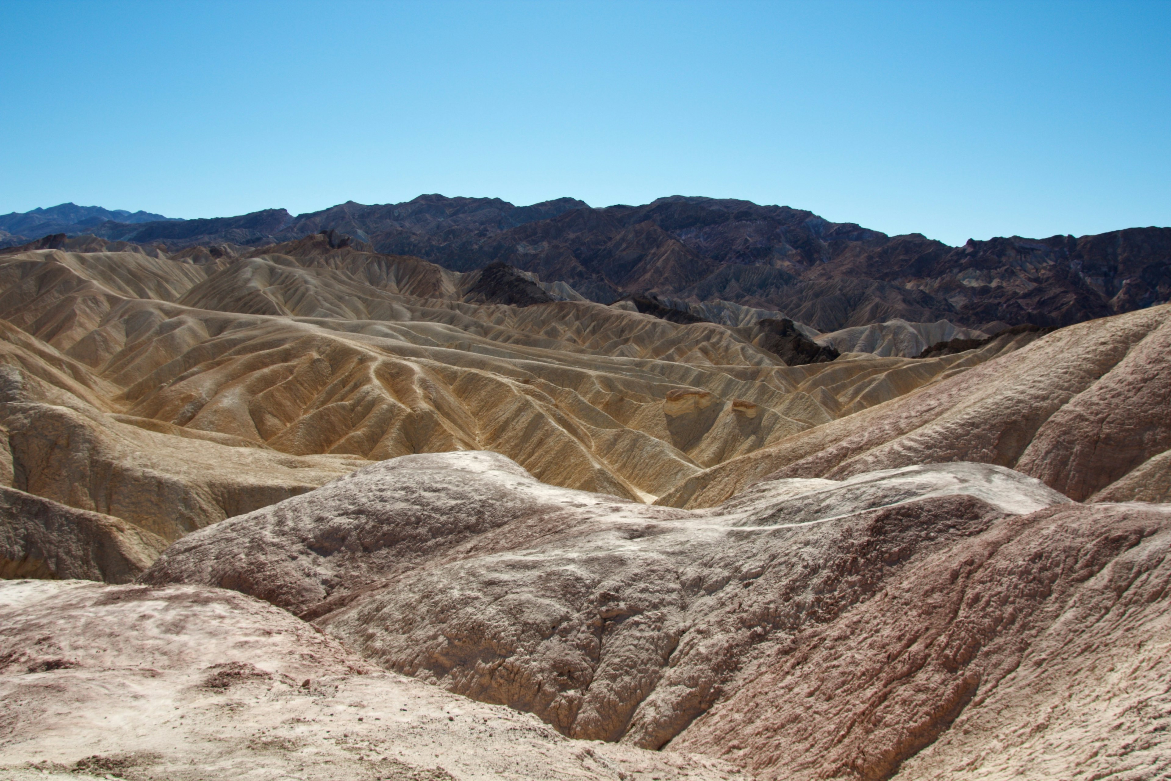 Weitläufige aride Landschaft mit bunten Gesteinsschichten unter der Sonne