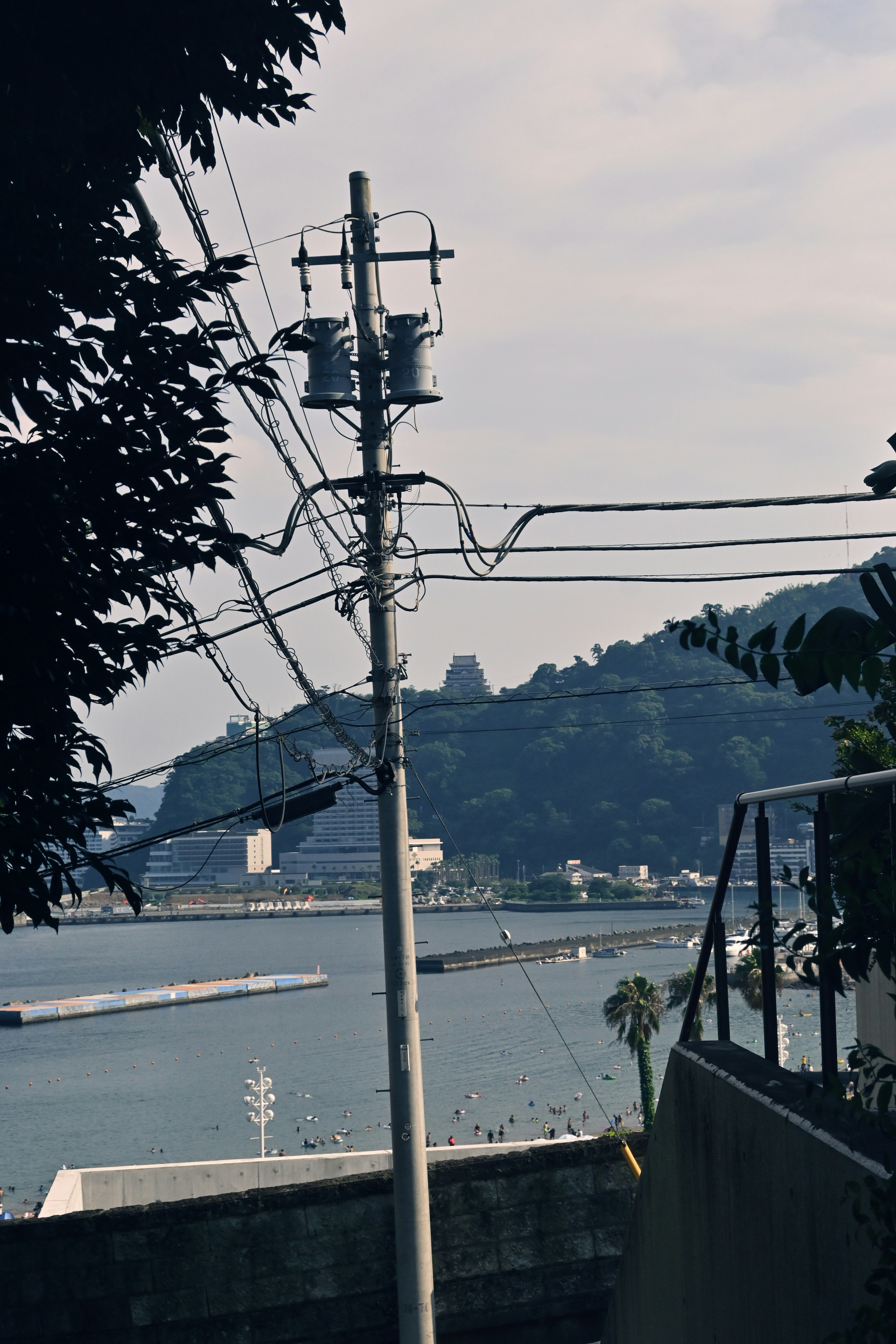 Blick auf das Meer und die Berge mit einem Strommast und Drähten