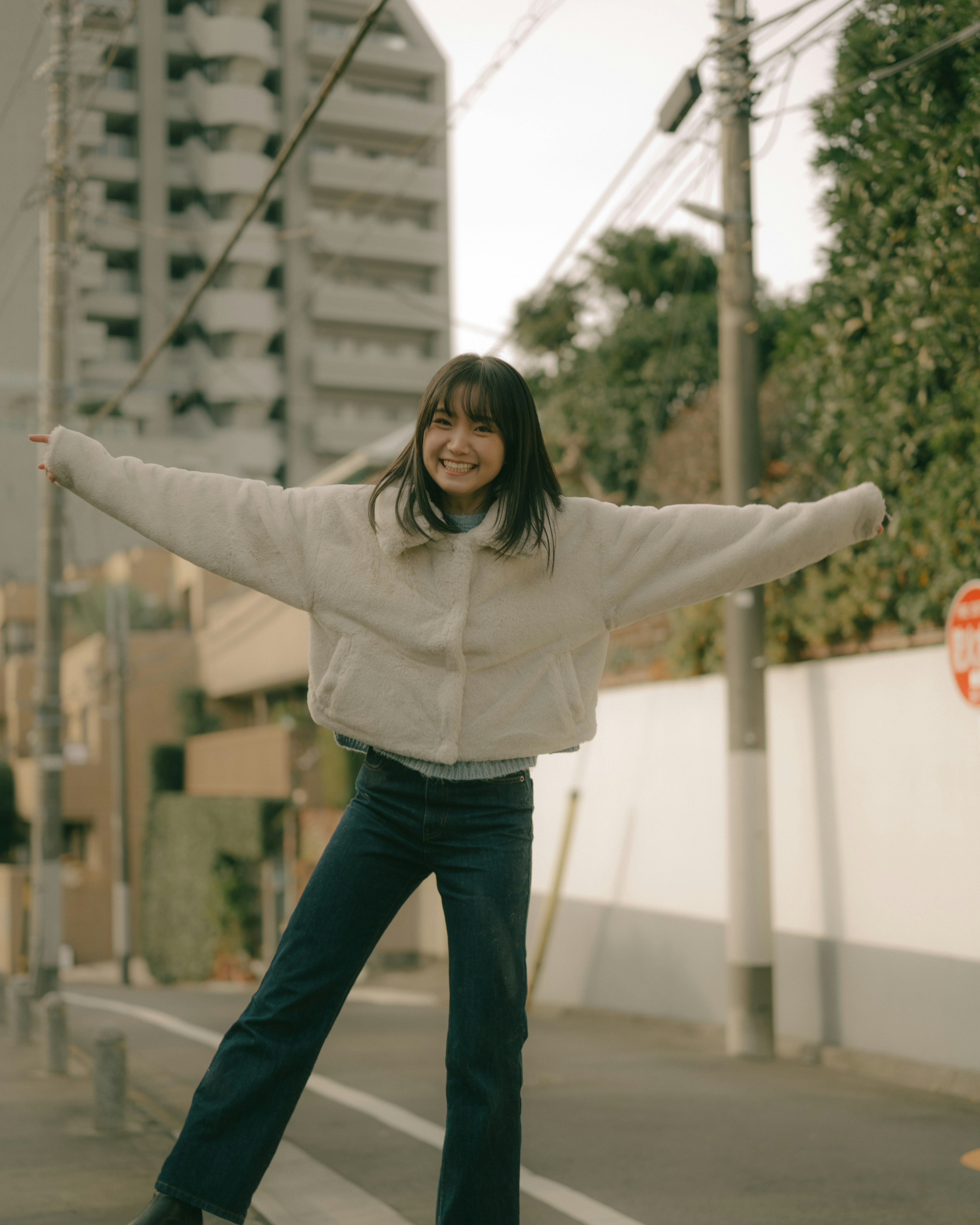 A smiling woman standing joyfully in the street showcasing casual fashion