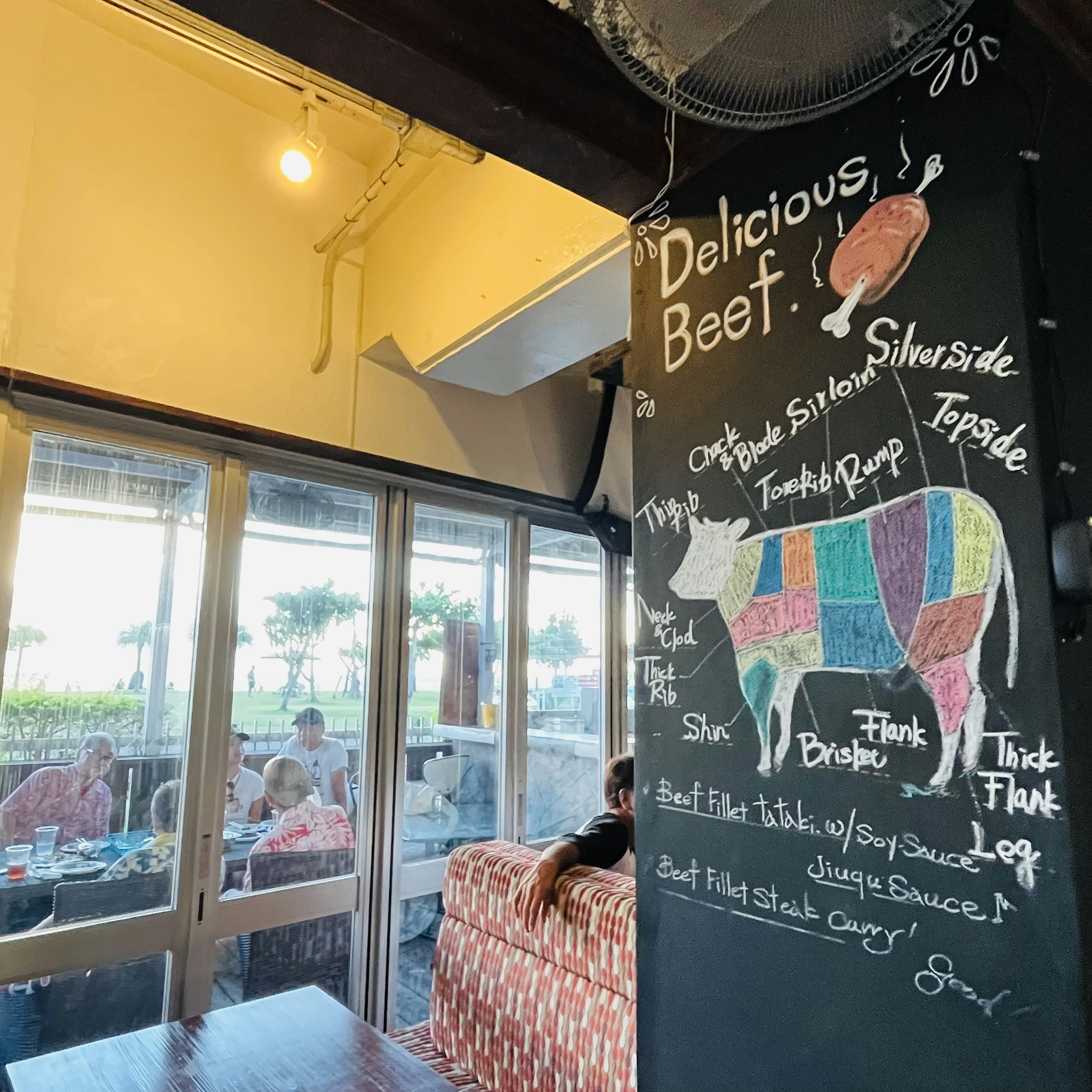 Intérieur d'un café avec un tableau noir affichant un diagramme de vache et des plats de viande délicieuse