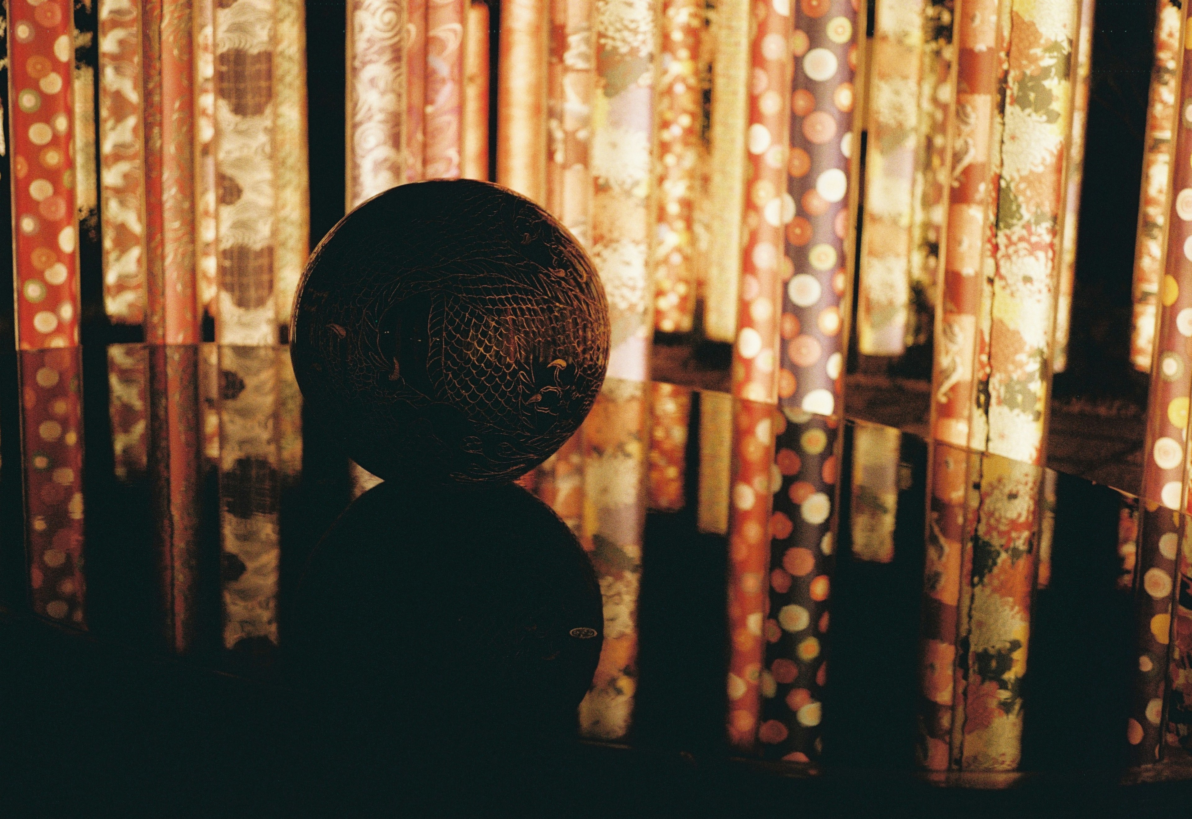 Reflective black sphere with colorful patterned background lights