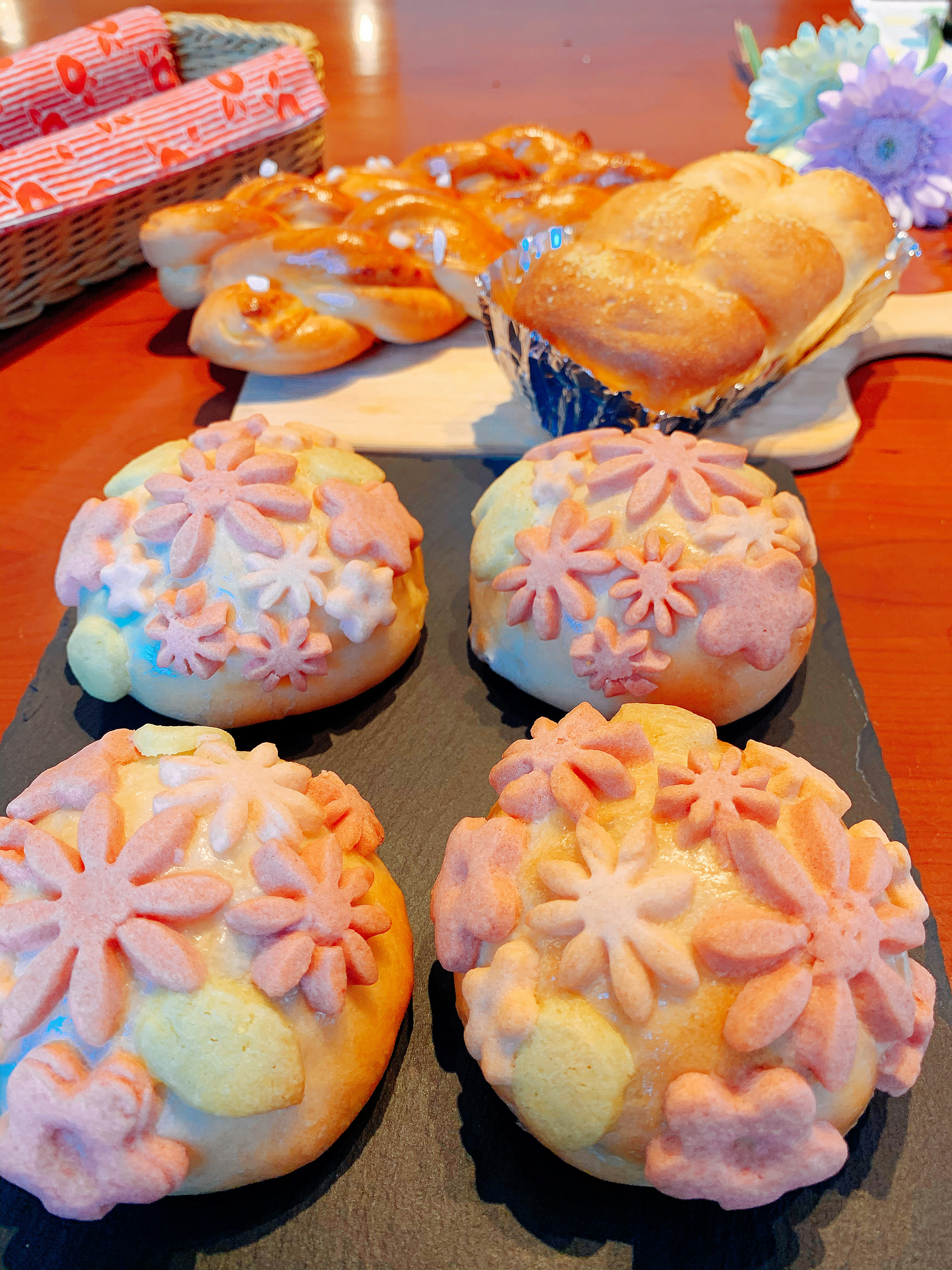 Una mesa con bollos decorados con flores y pasteles