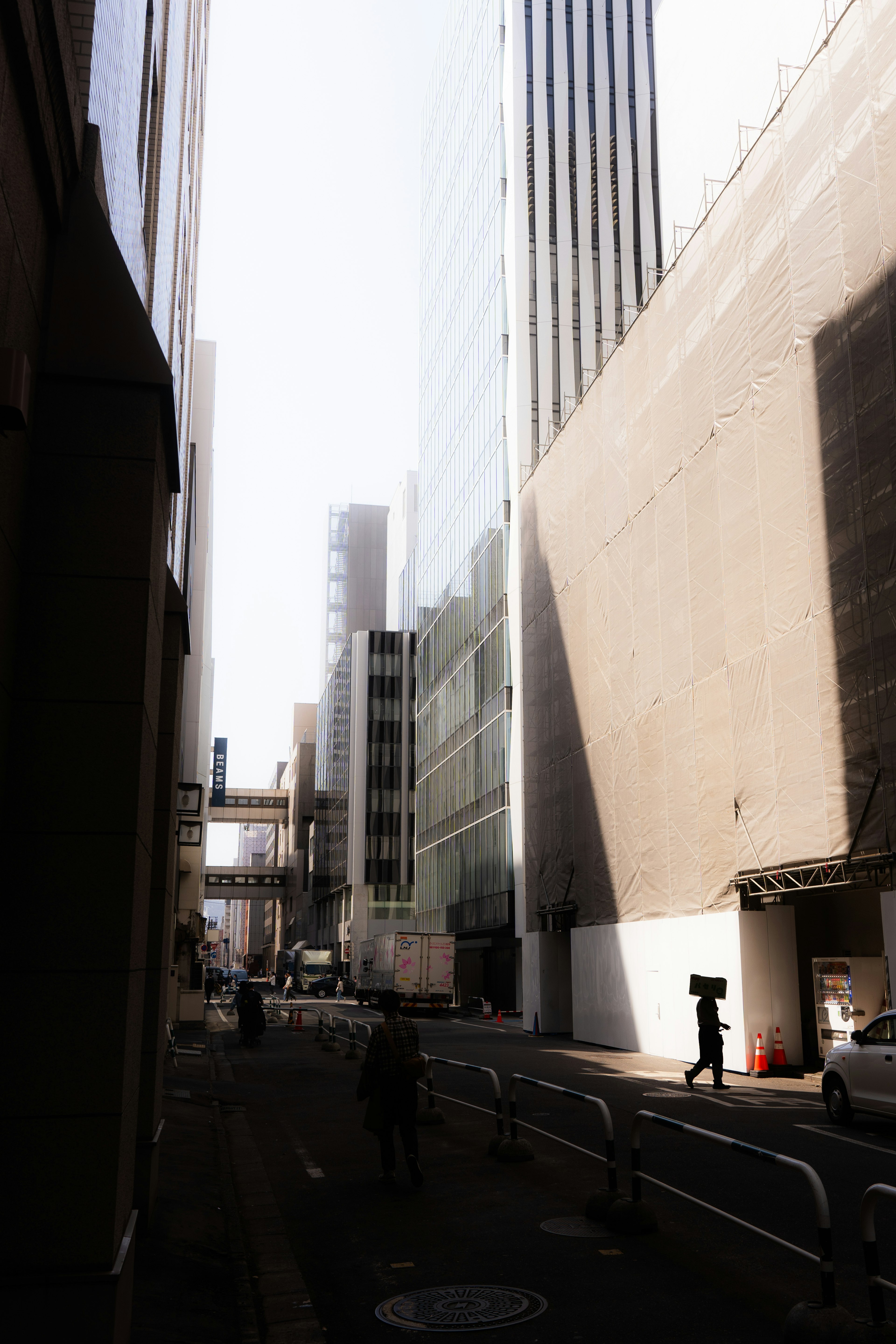 Escena de calle estrecha con altos edificios proyectando largas sombras