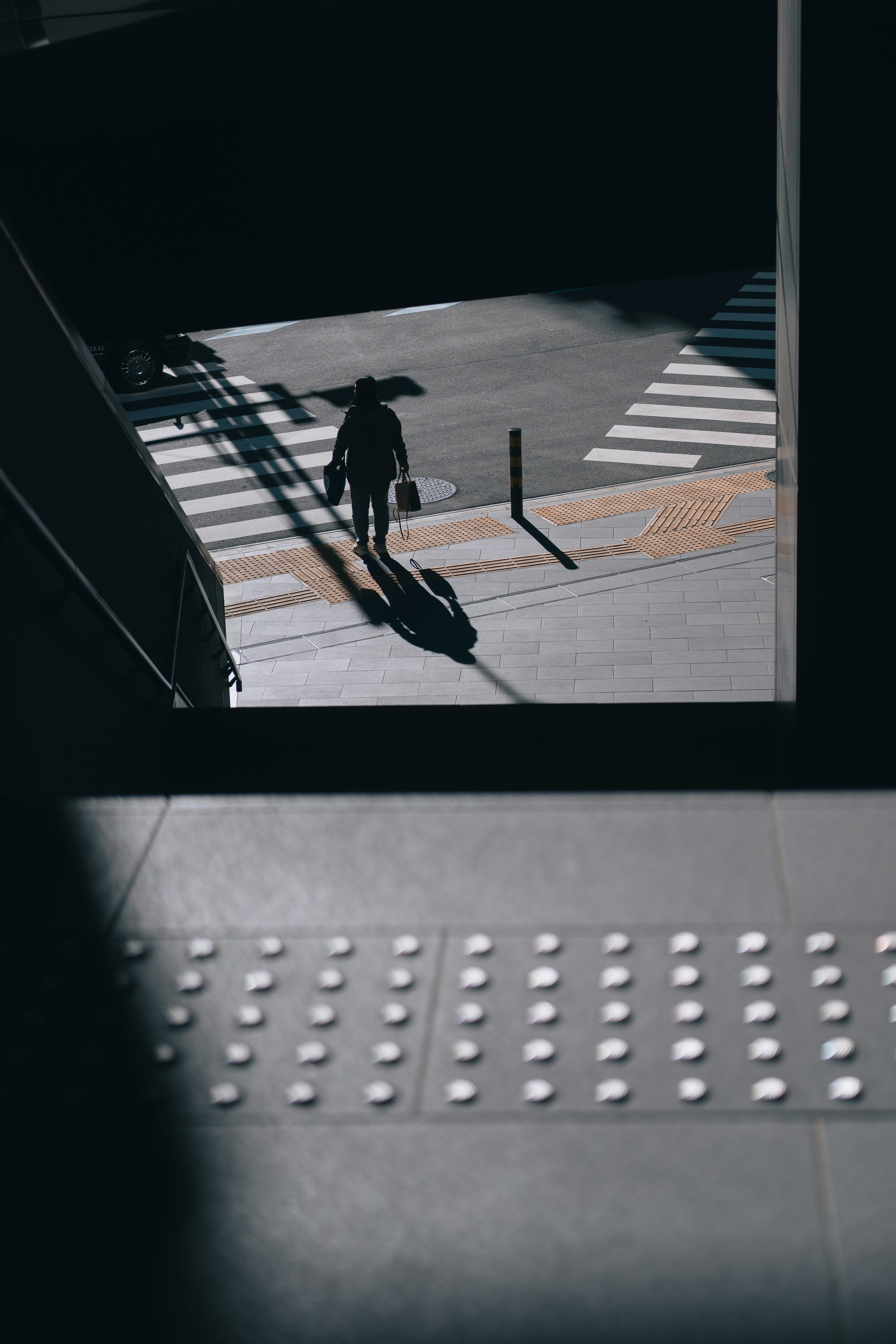 Eine Person, die im Schatten an einem Zebrastreifen läuft