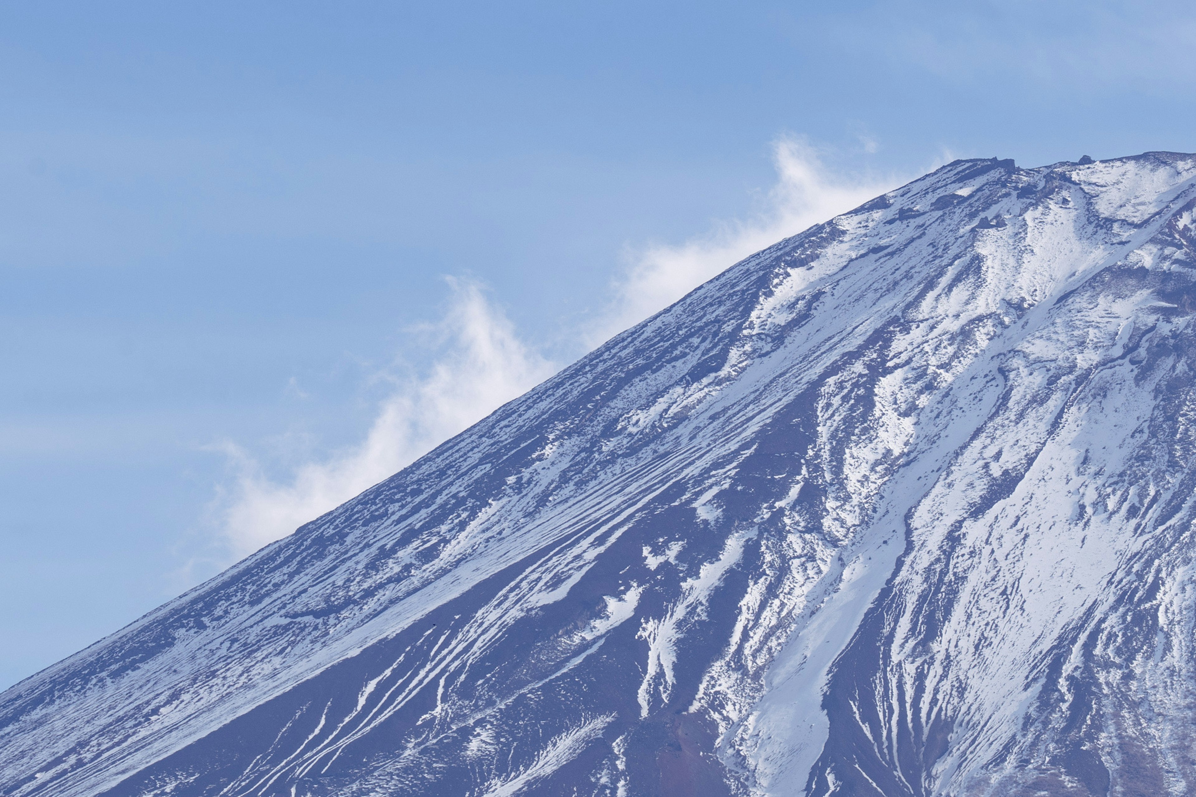 Snow-covered volcano peak against a blue sky