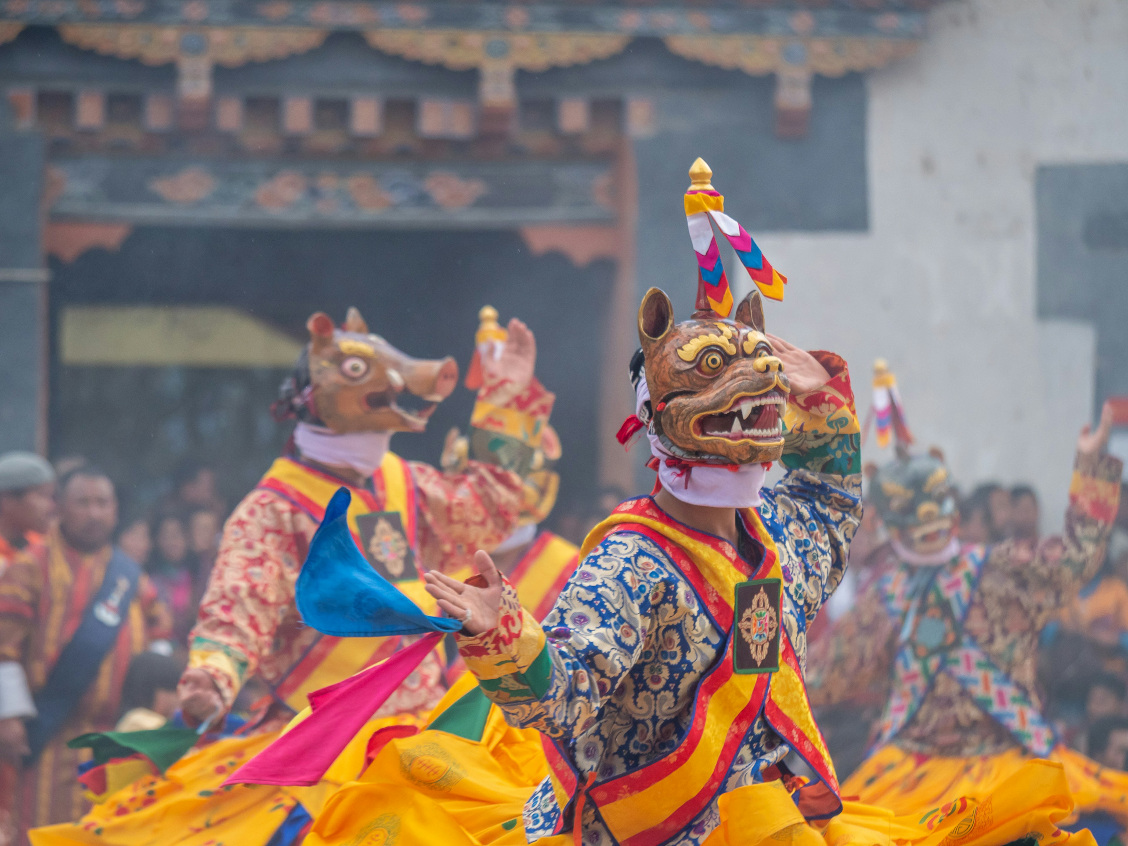 Dancers in traditional costumes wearing masks performing at a vibrant festival