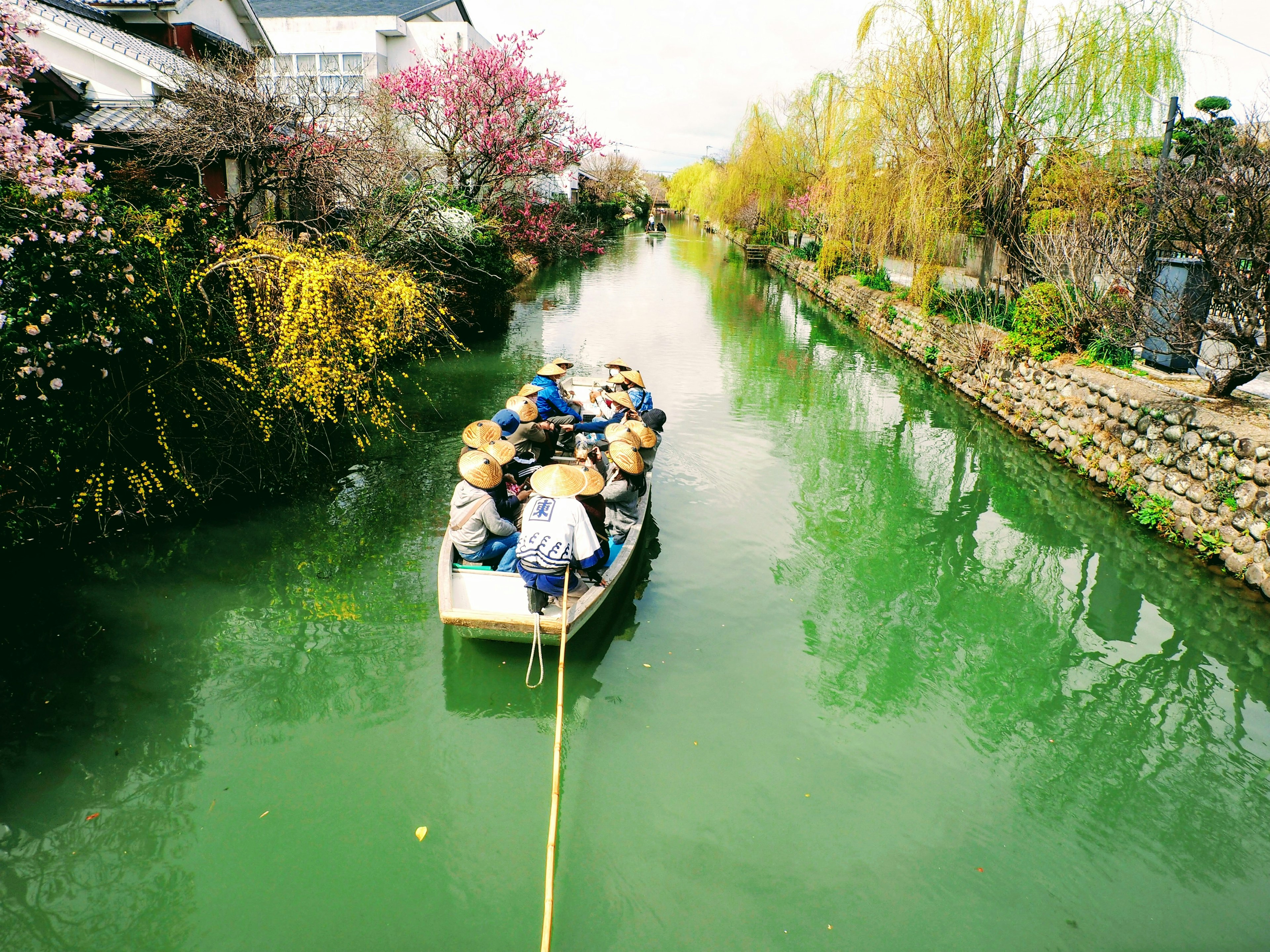 Un bateau avec des personnes naviguant dans un canal vert entouré de fleurs en fleurs