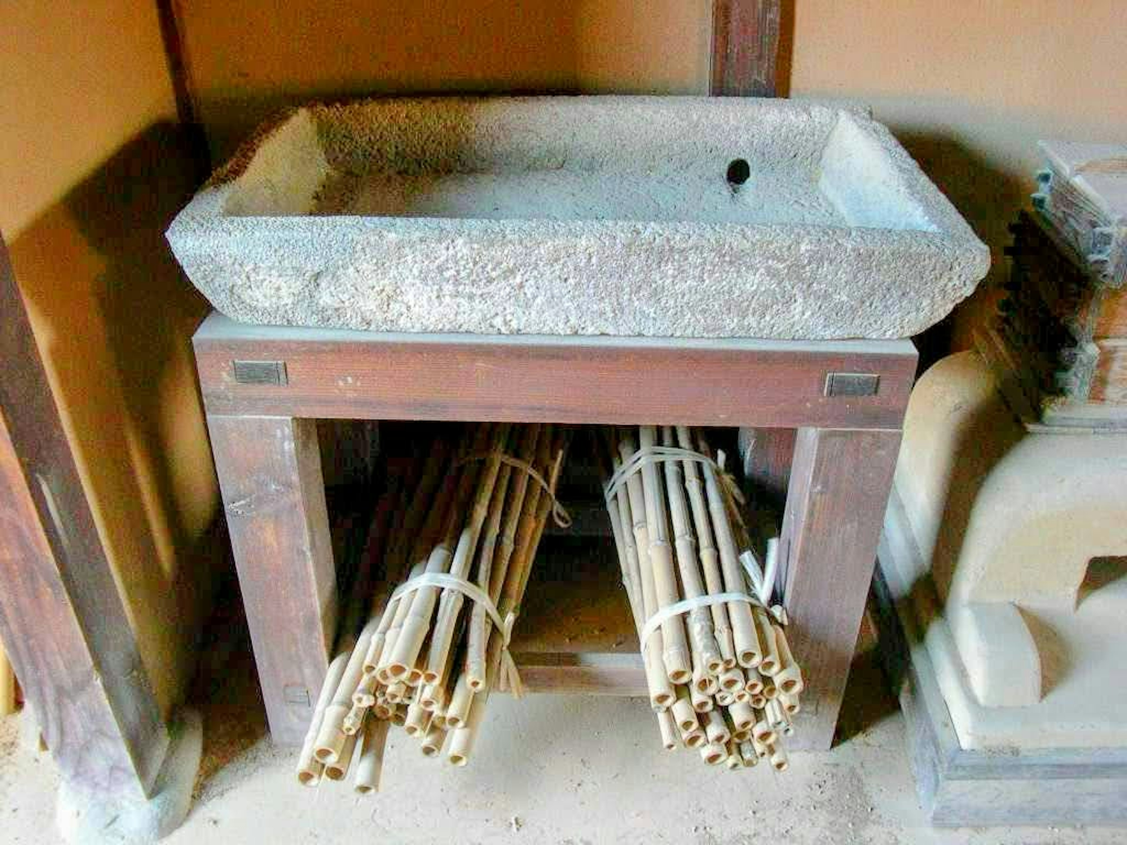 Stone sink on wooden stand with bundled bamboo underneath