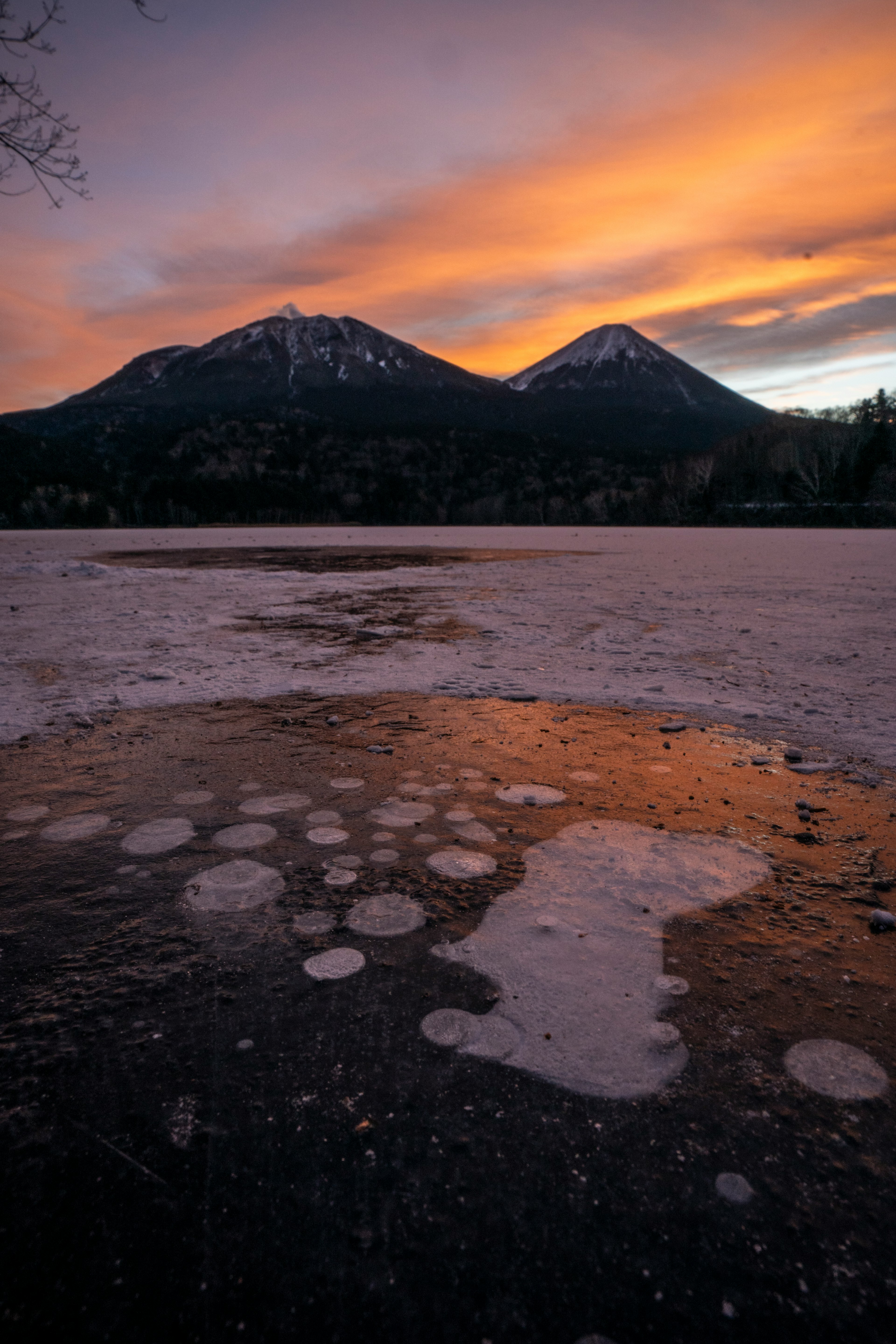 Beautiful landscape of mountains and frozen lake under sunset sky