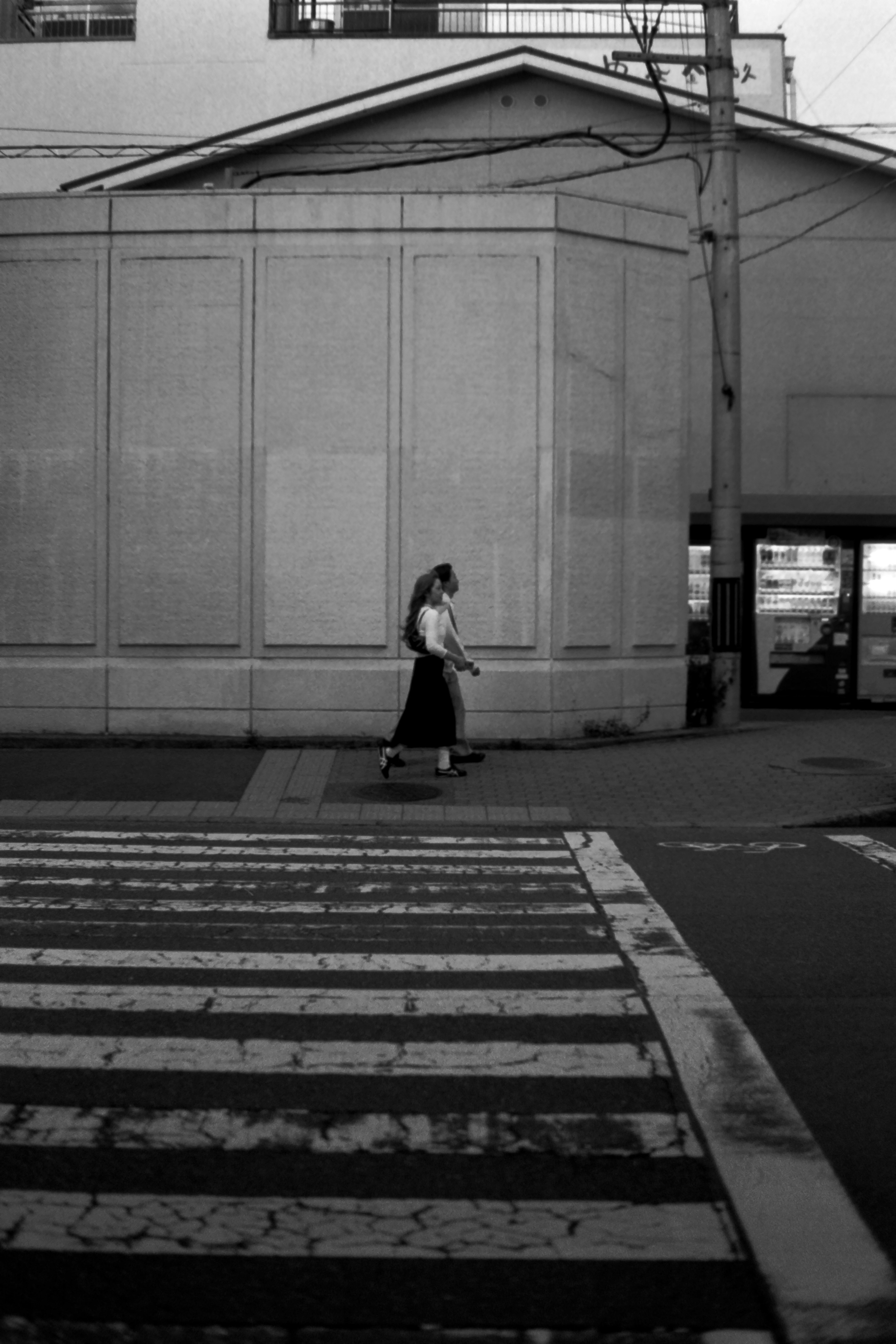 Une femme marchant dans un passage piéton en noir et blanc avec un mur en arrière-plan