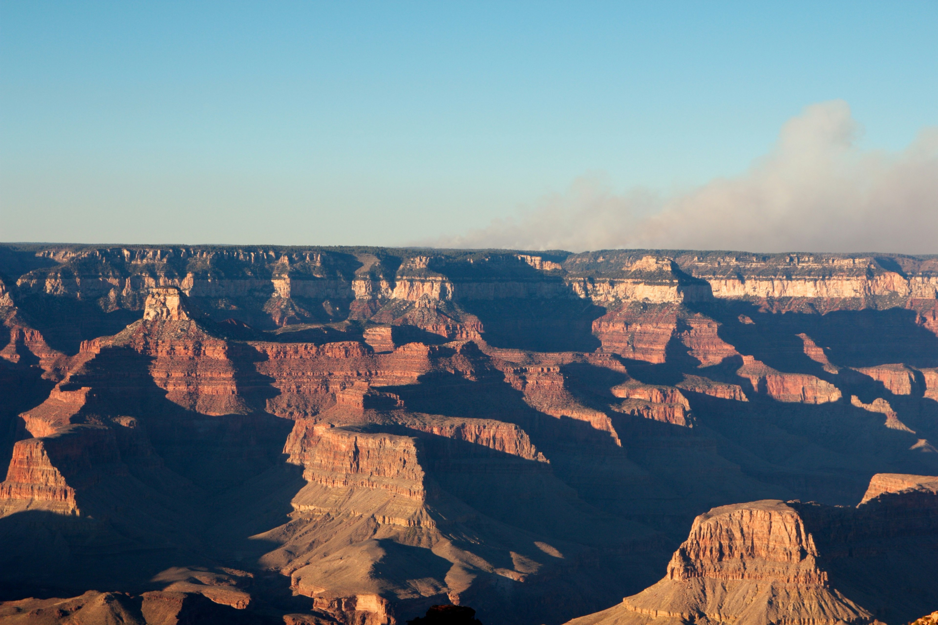 Breathtaking view of the Grand Canyon with reddish rock formations and clear blue sky