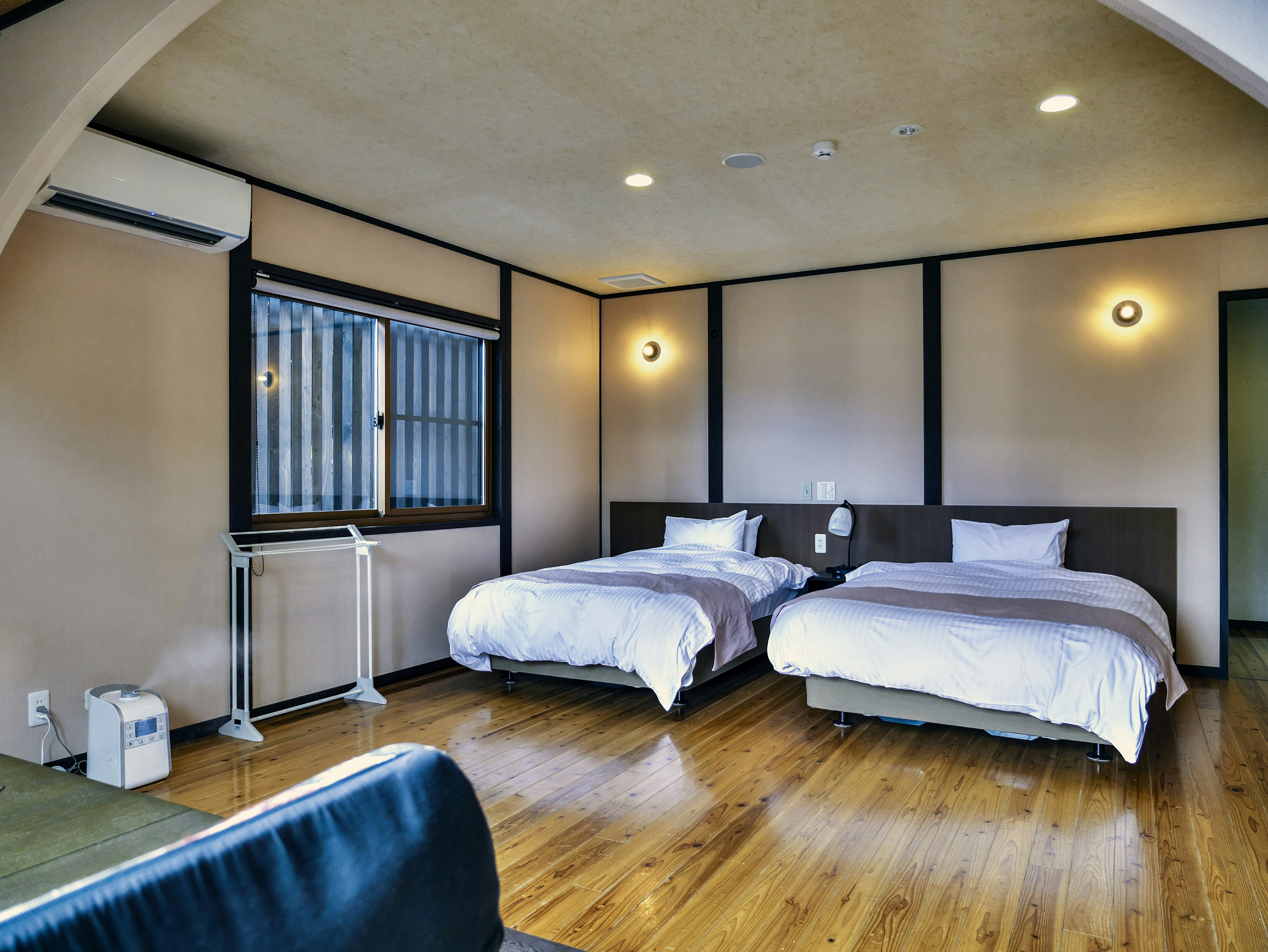 Modern and simple guest room featuring two beds wooden flooring and natural light from the window