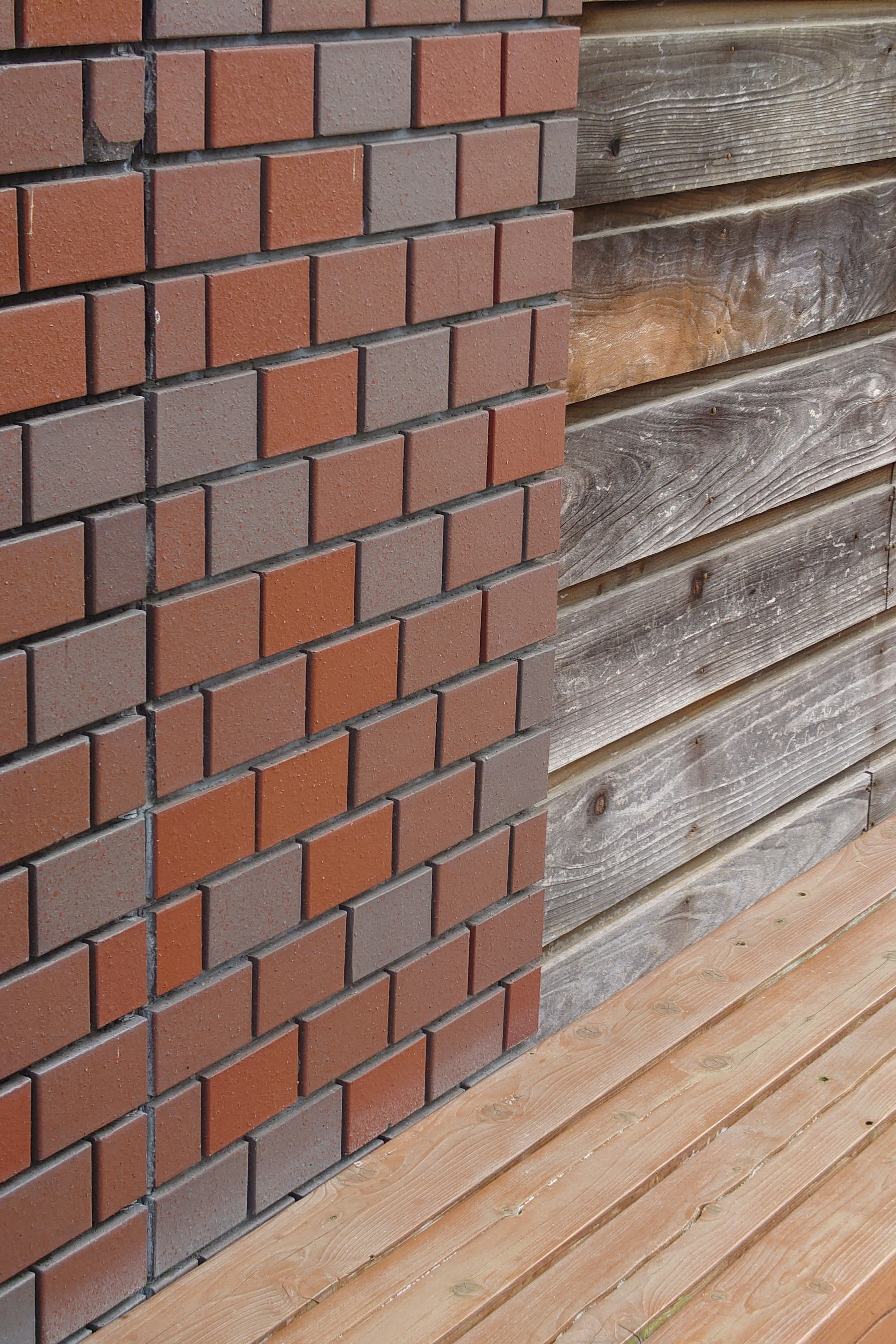 Image featuring a red-brown brick wall next to a wooden wall