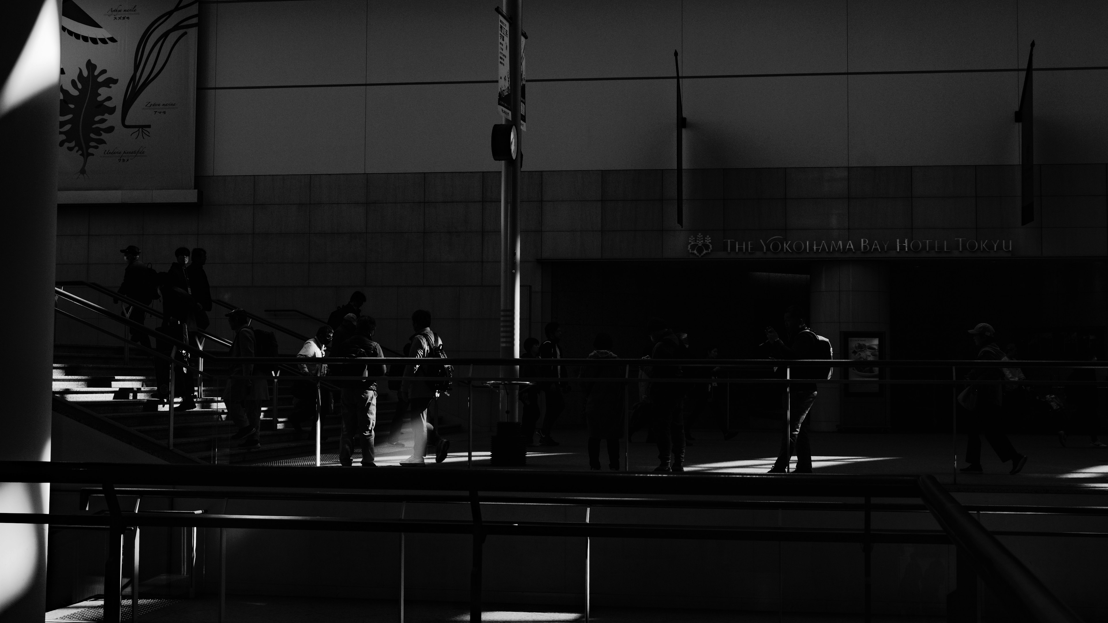 Black and white image of people moving in a modern building interior