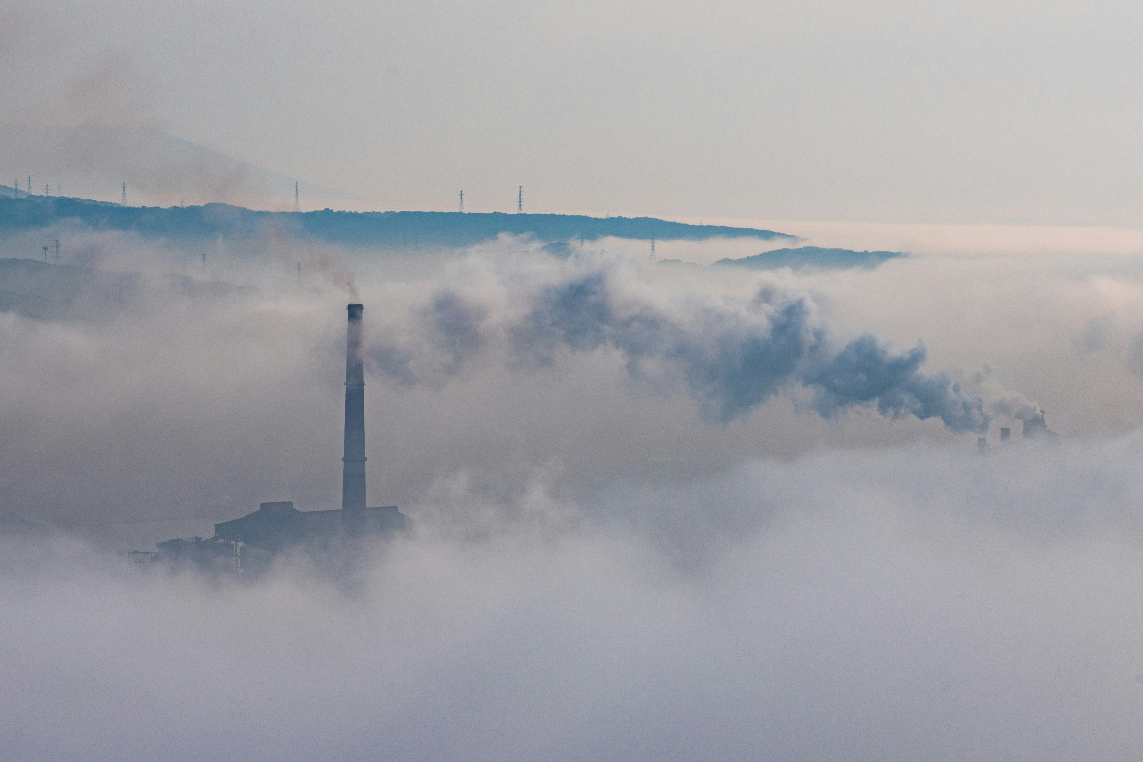 A smokestack emitting smoke surrounded by clouds