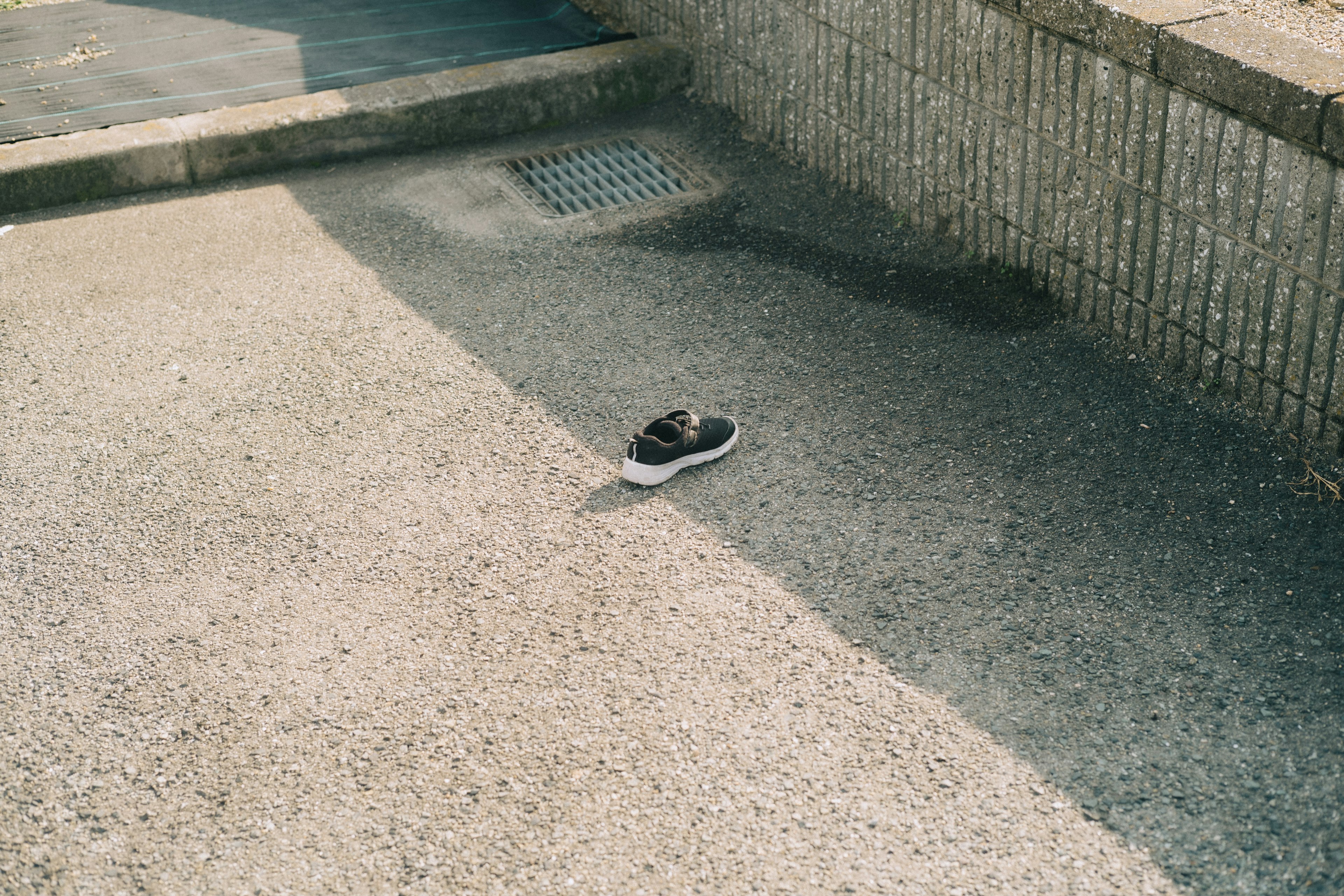 Une sneaker noire posée sur un sol pavé