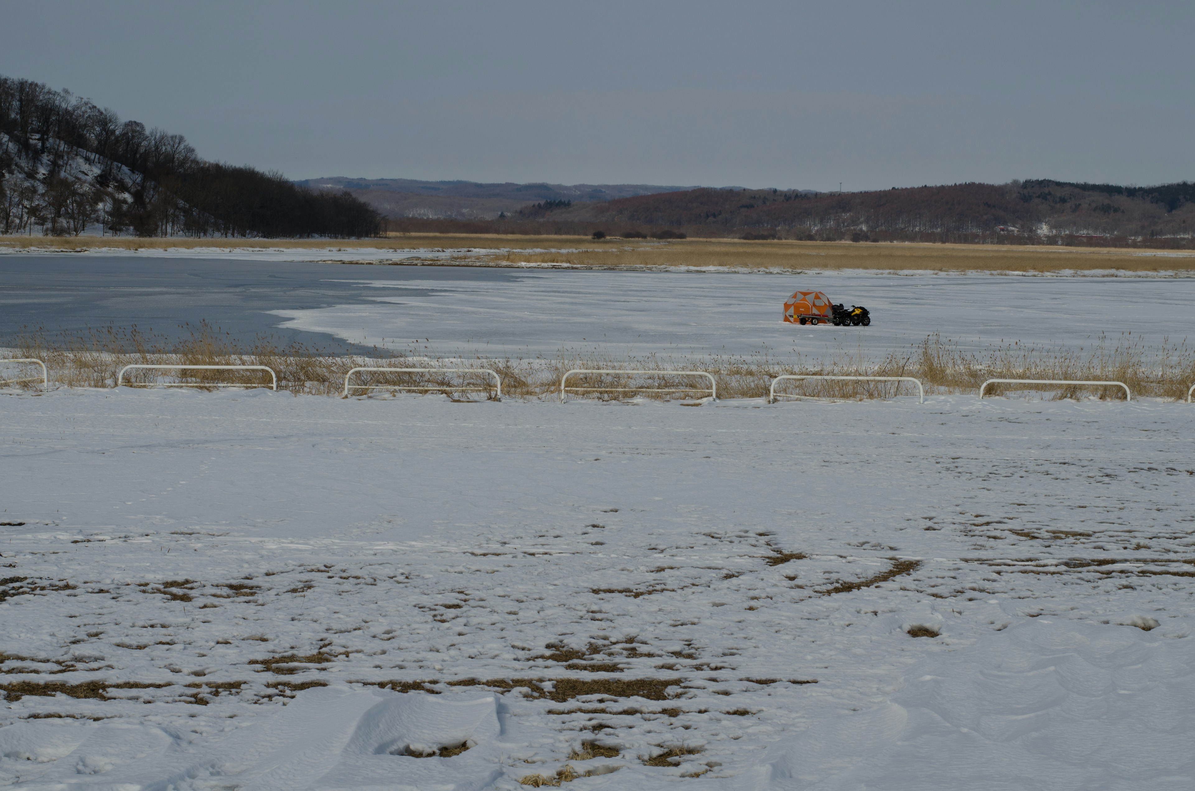 Snow-covered landscape with an orange vehicle in the distance