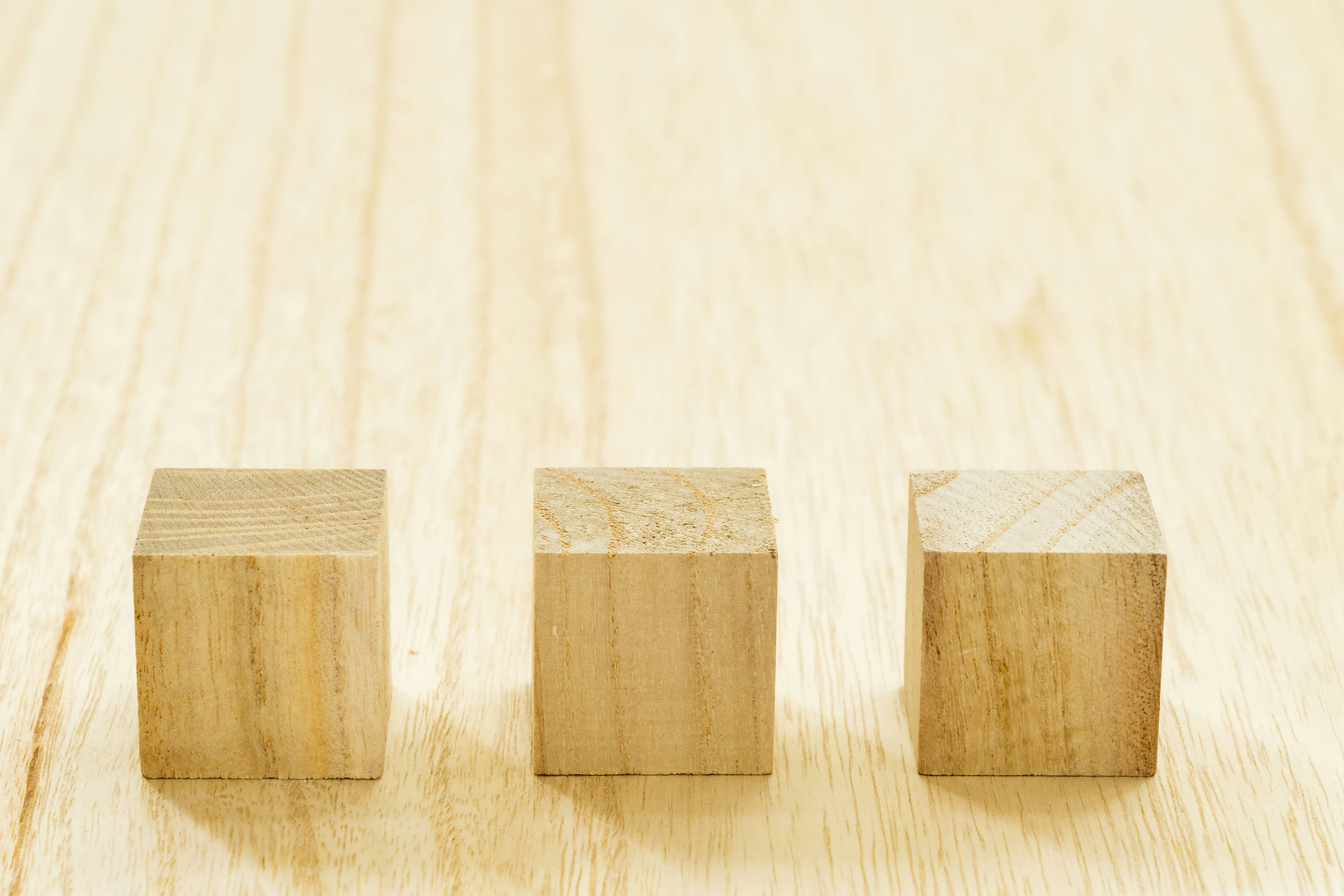 Three wooden cubes arranged on a light wooden surface