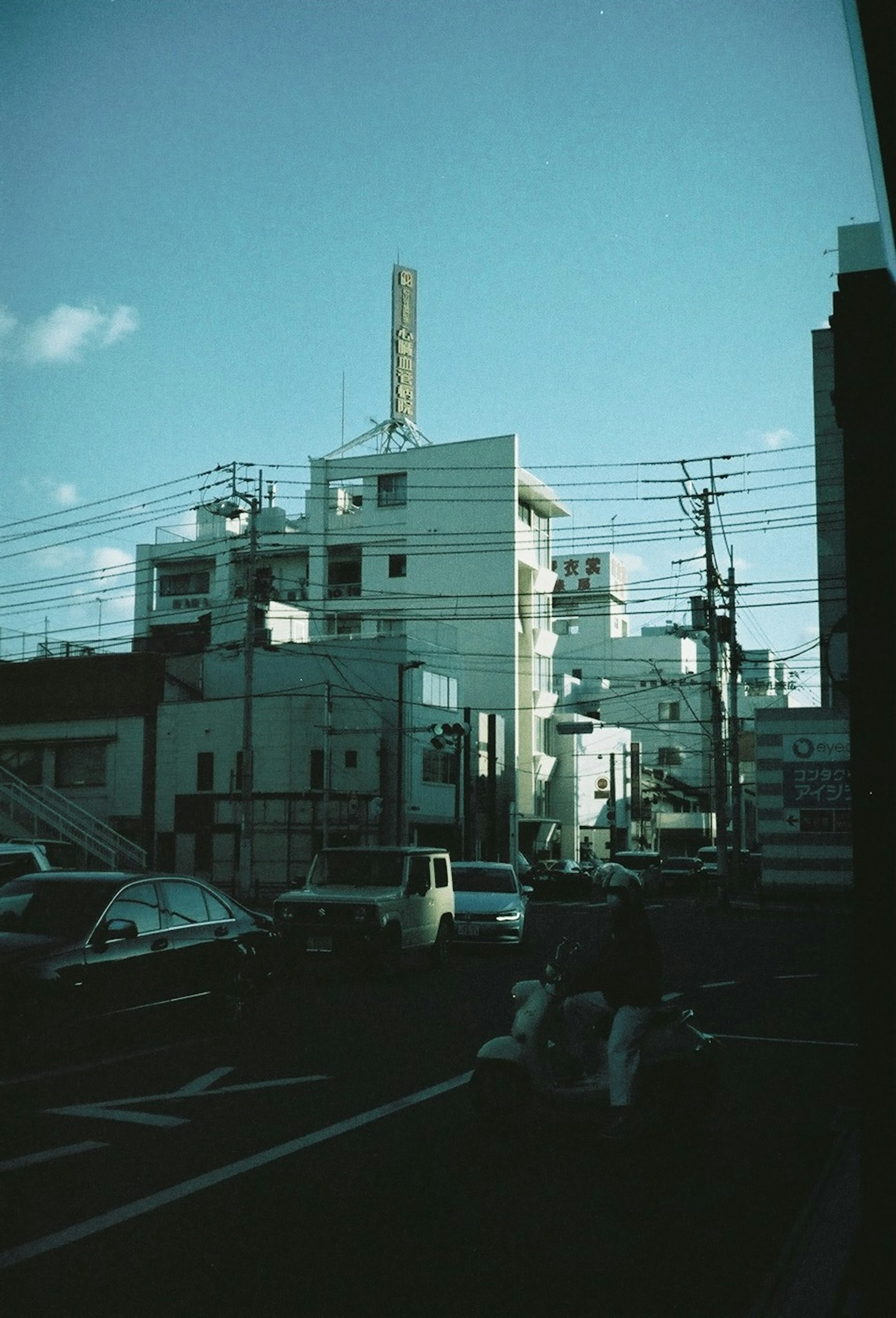 Escena urbana con edificios blancos y cielo azul con líneas eléctricas que se cruzan