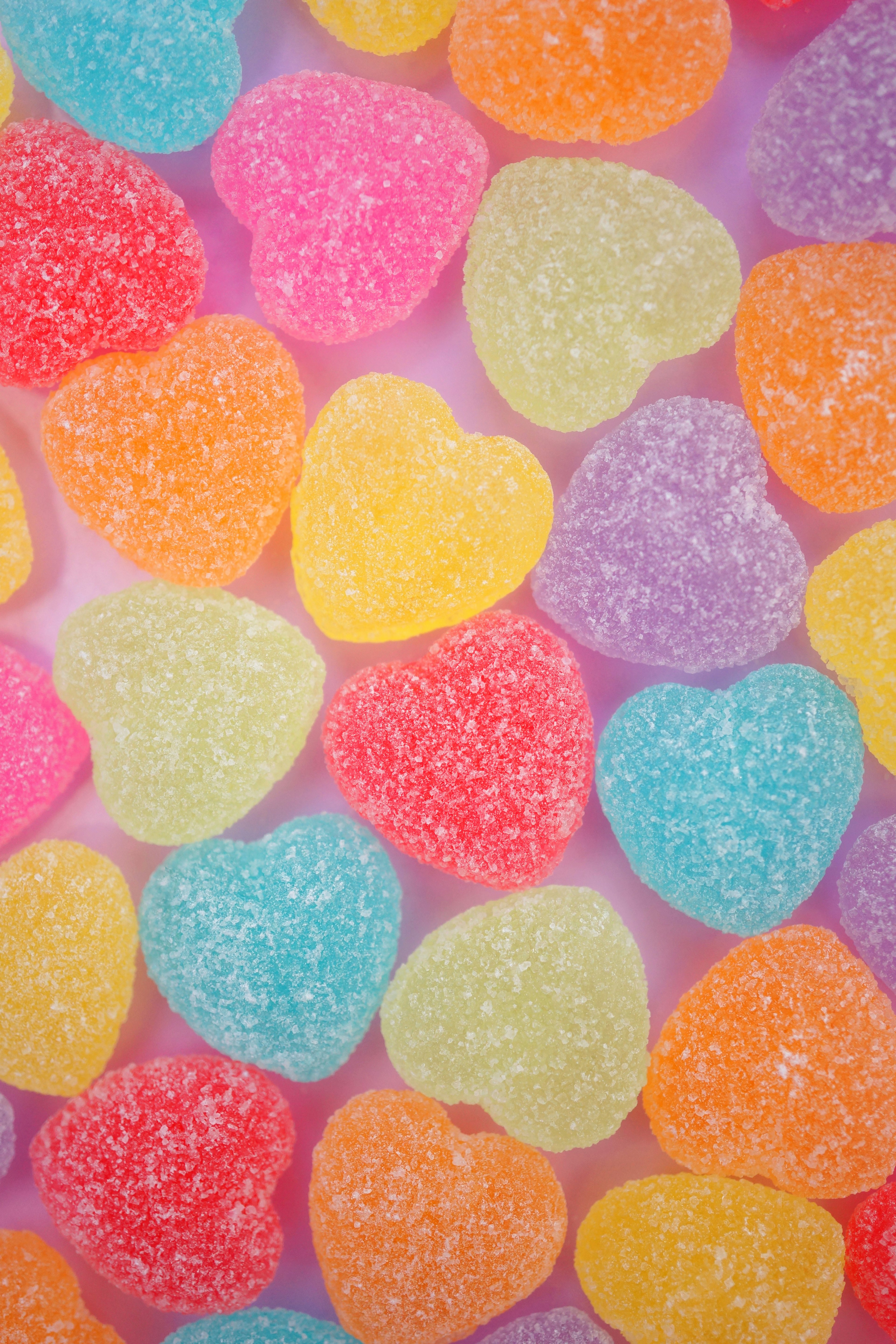 Caramelos de gelatina en forma de corazón de colores esparcidos sobre un fondo