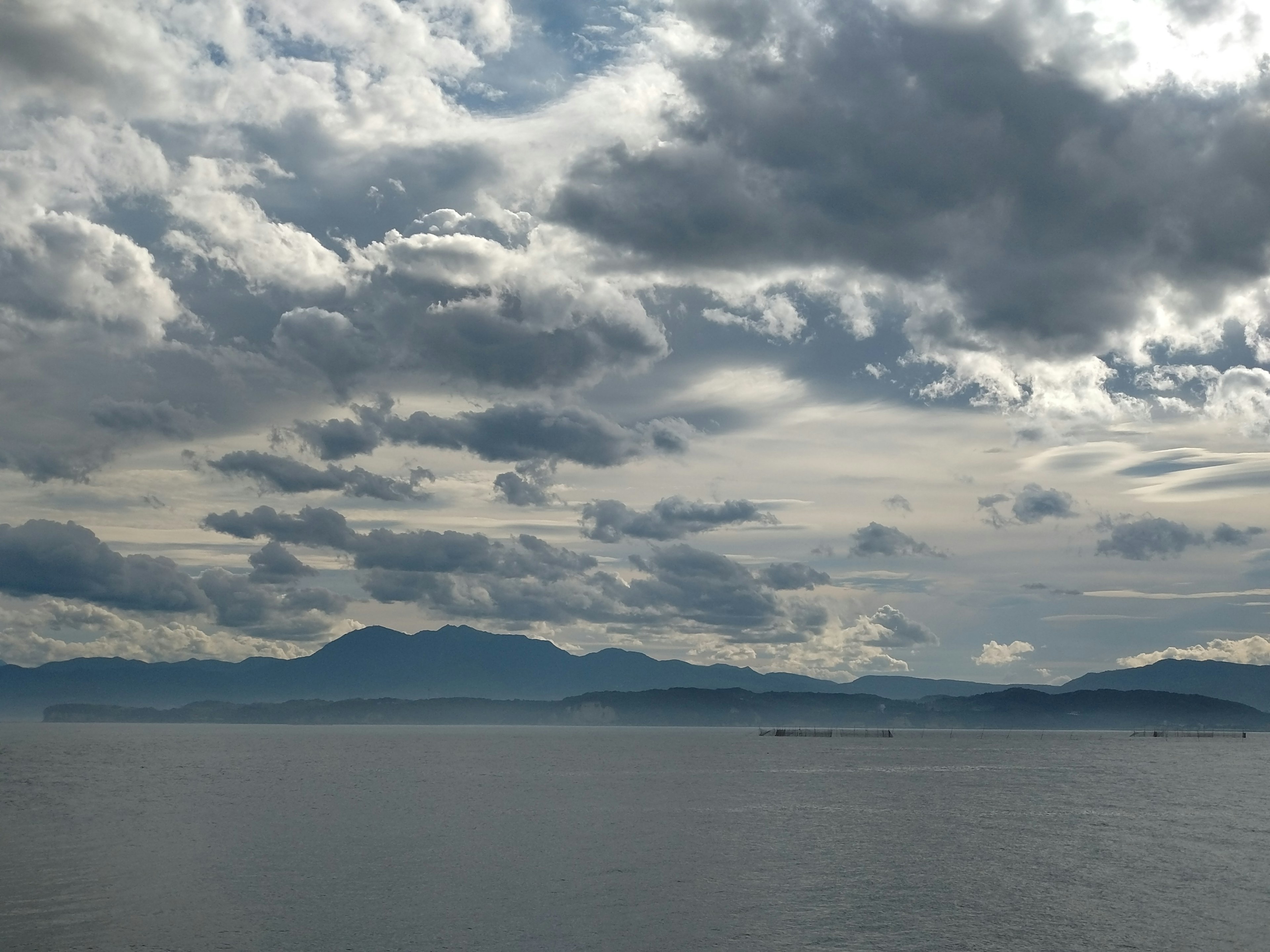 海洋和山脈的景觀 多雲的天空和寧靜的水面