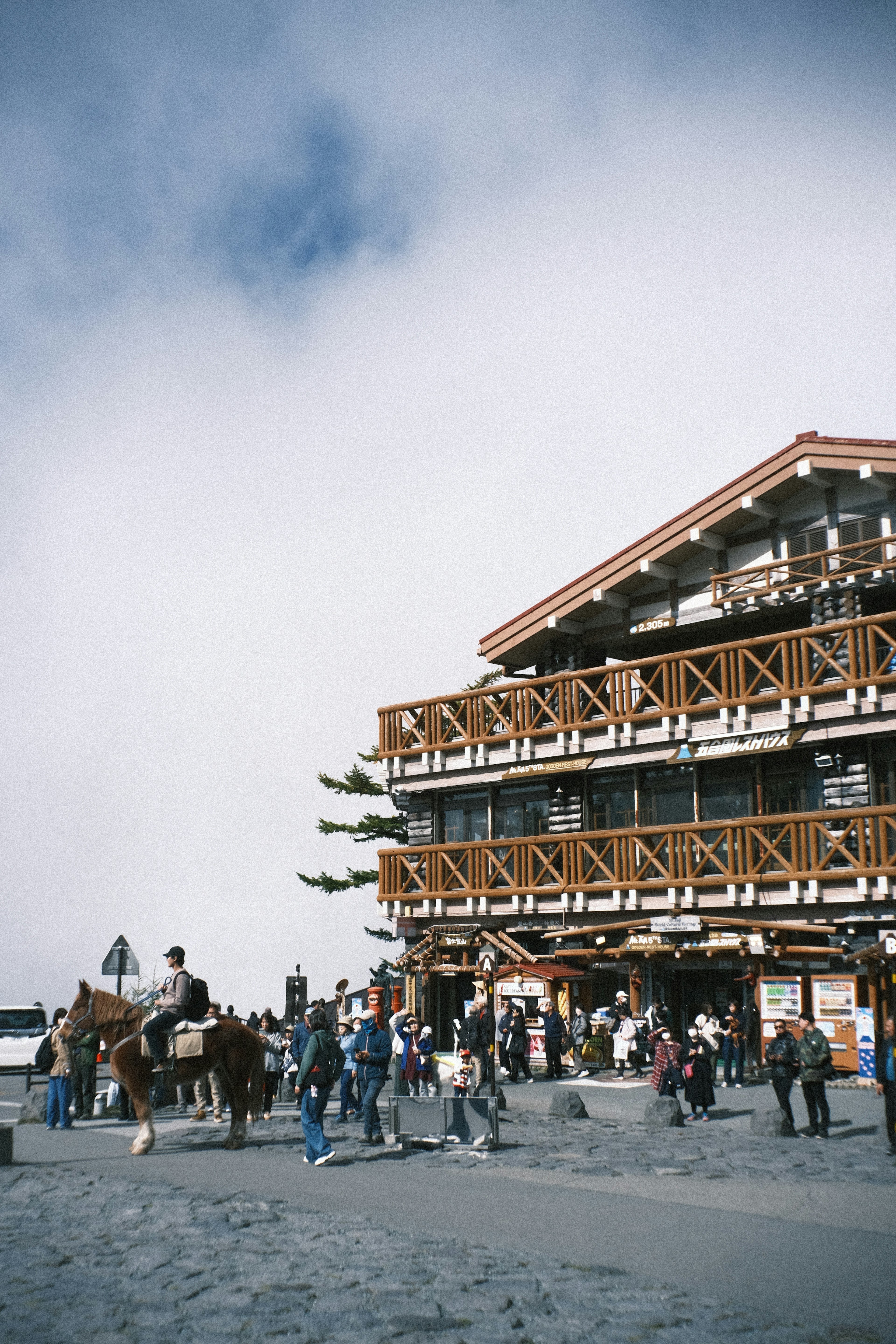 山の小屋と人々が集まる風景 馬に乗った人がいる