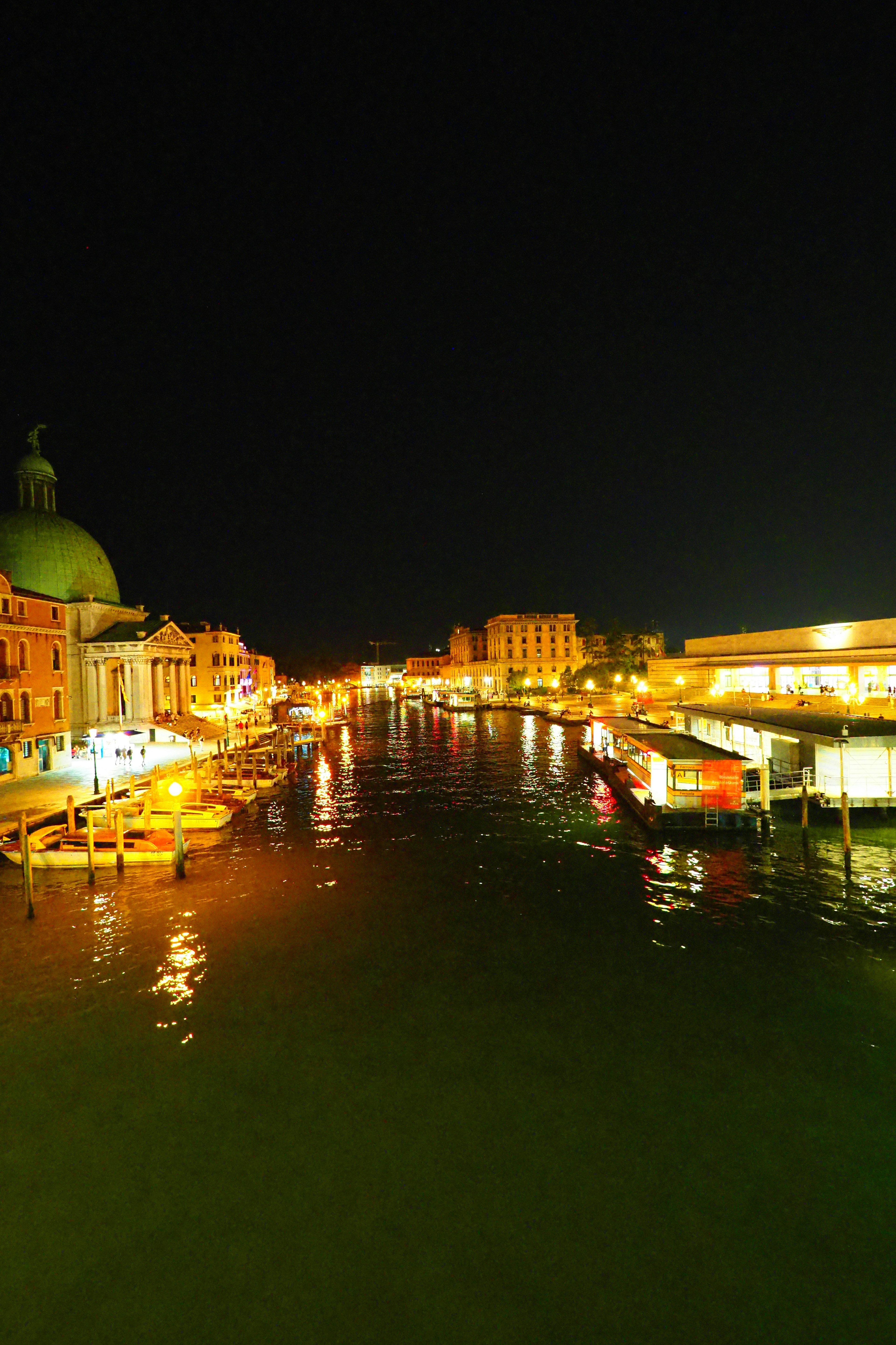 Vista nocturna de un canal con edificios iluminados y reflejos