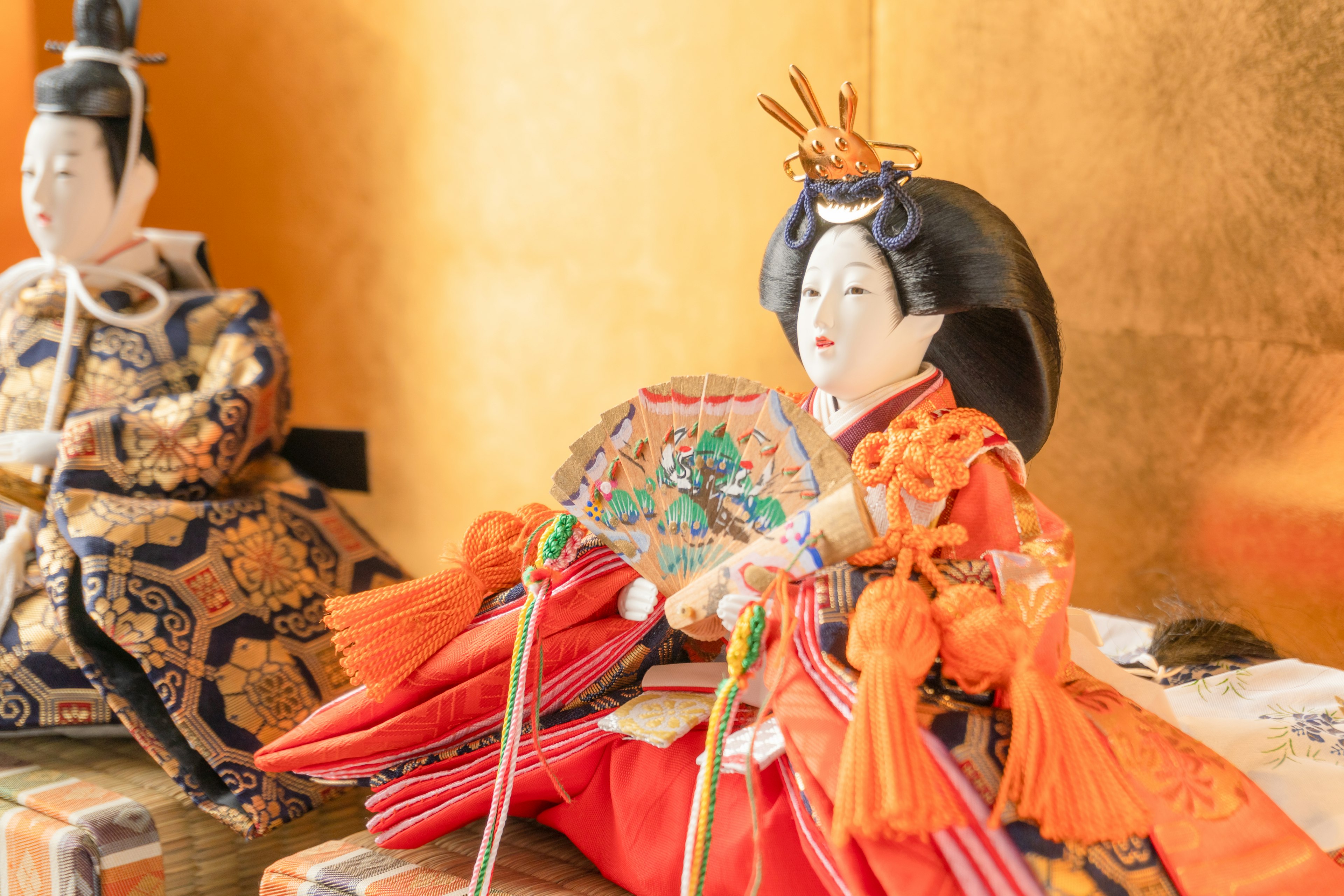 Muñecas hina japonesas tradicionales exhibidas con una figura femenina llamativa en ropa vibrante