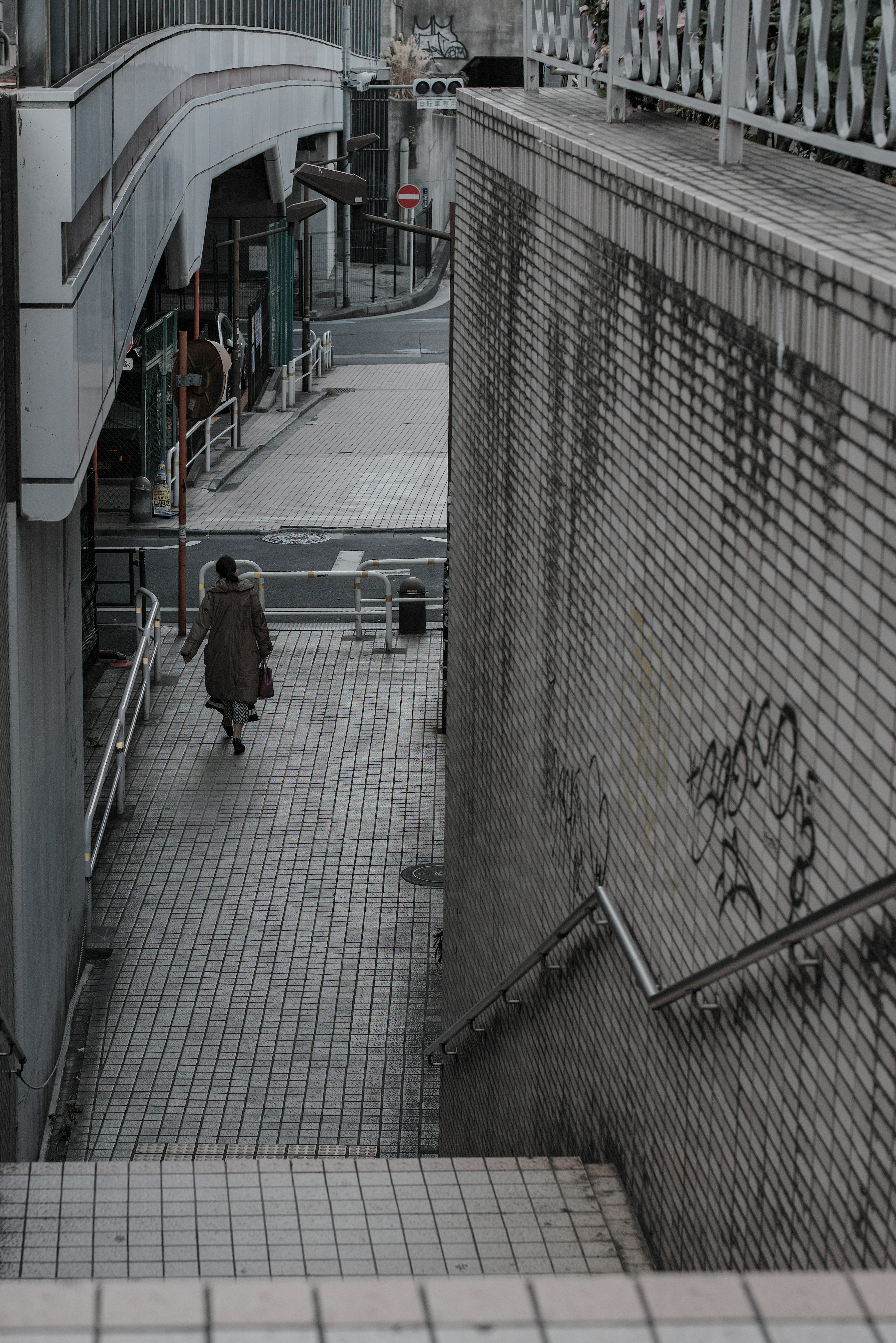 Una persona caminando en una calle tranquila con edificios monocromáticos