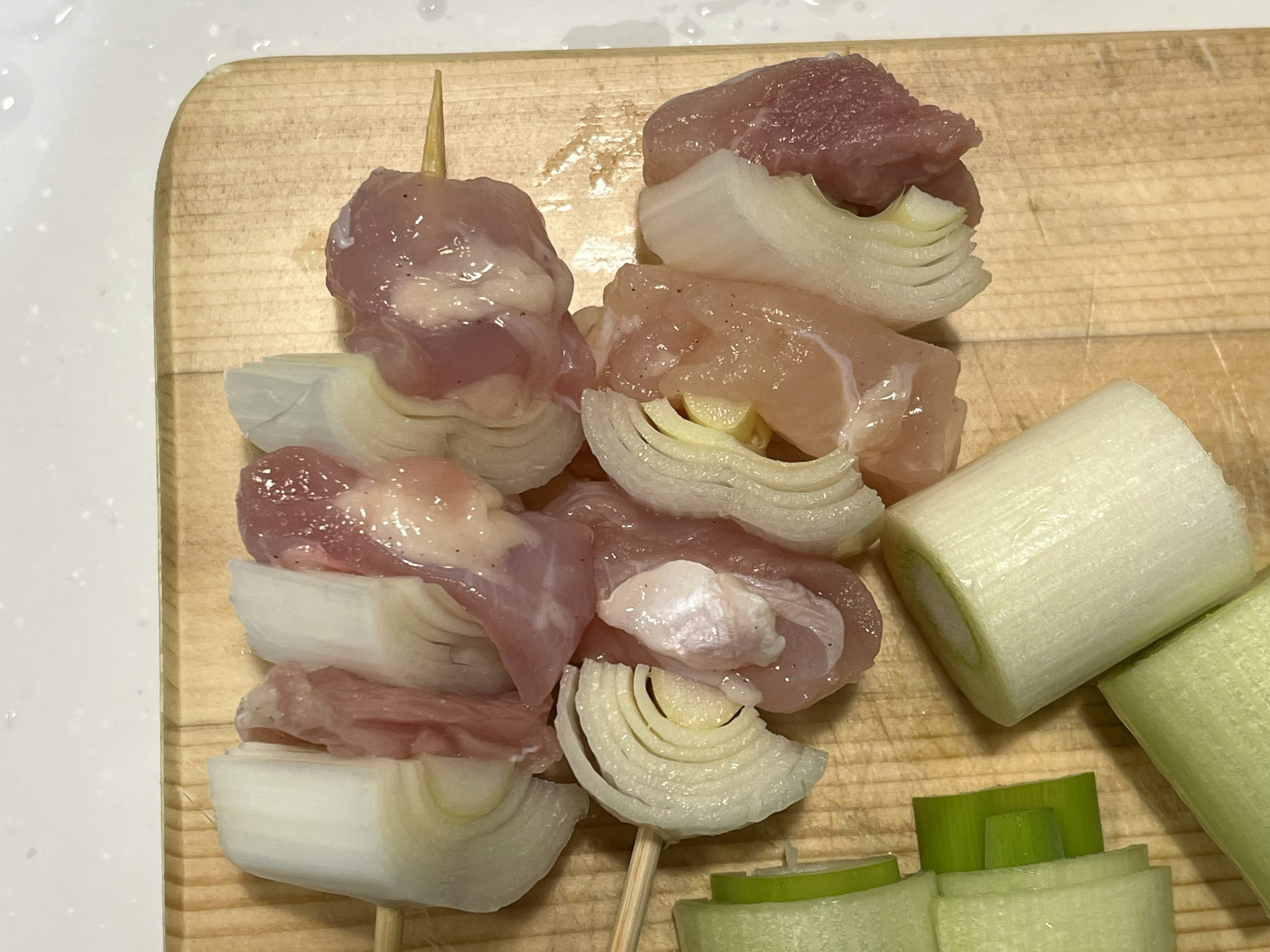 Porc en brochette enveloppé dans des oignons verts sur une planche à découper en bois