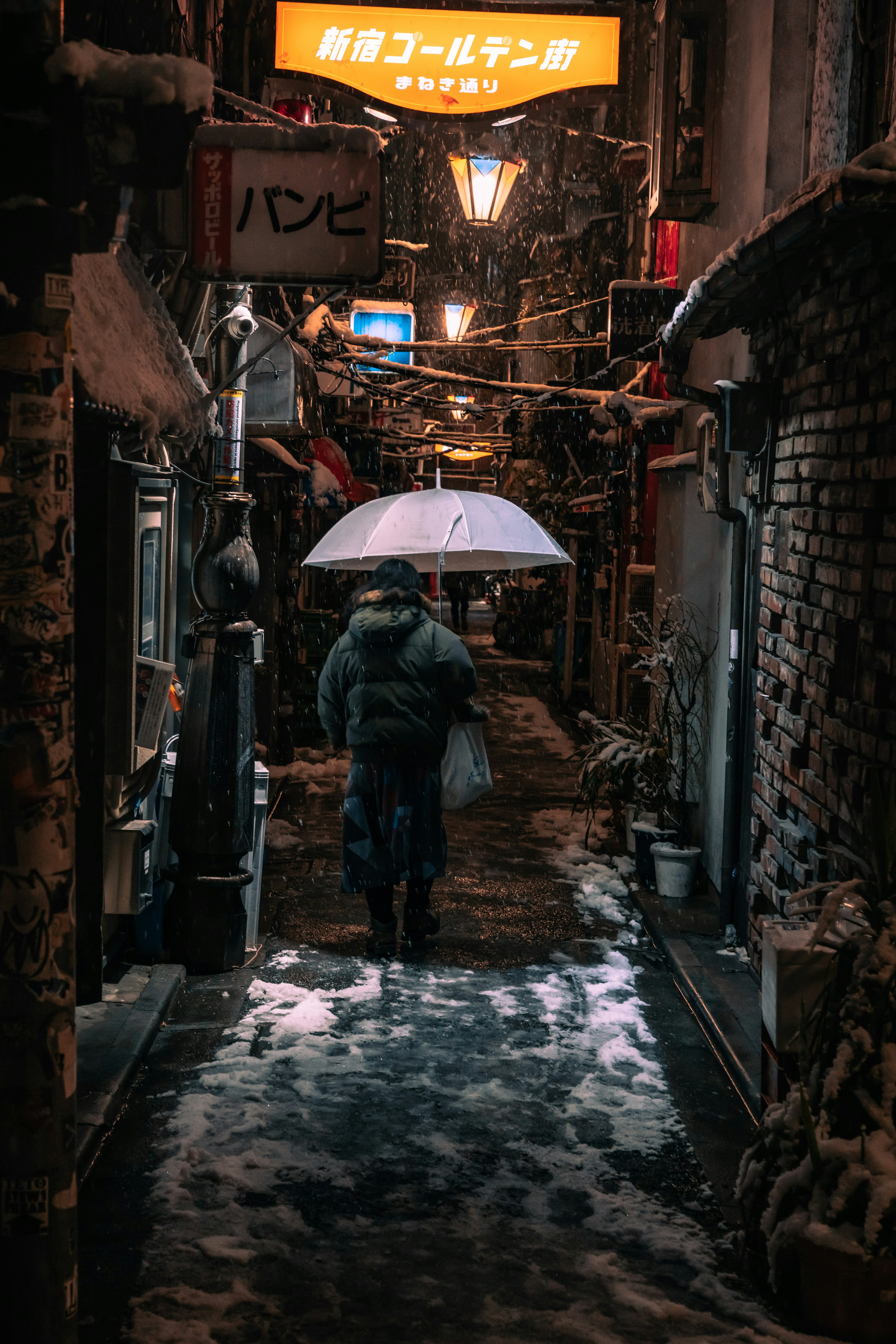 雪が降る路地を傘をさして歩く人と古い建物の風景