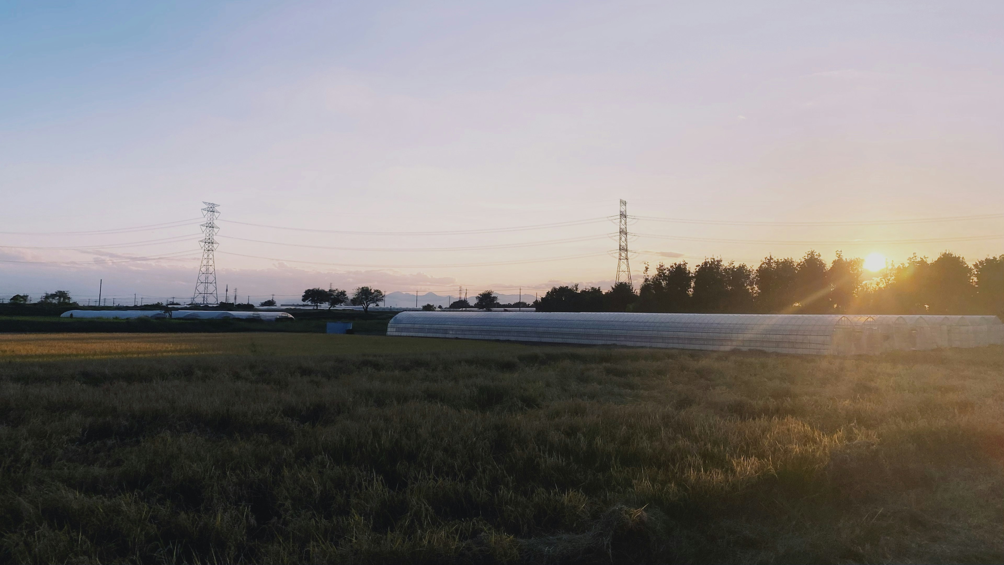 Rural landscape at sunset with high voltage power lines