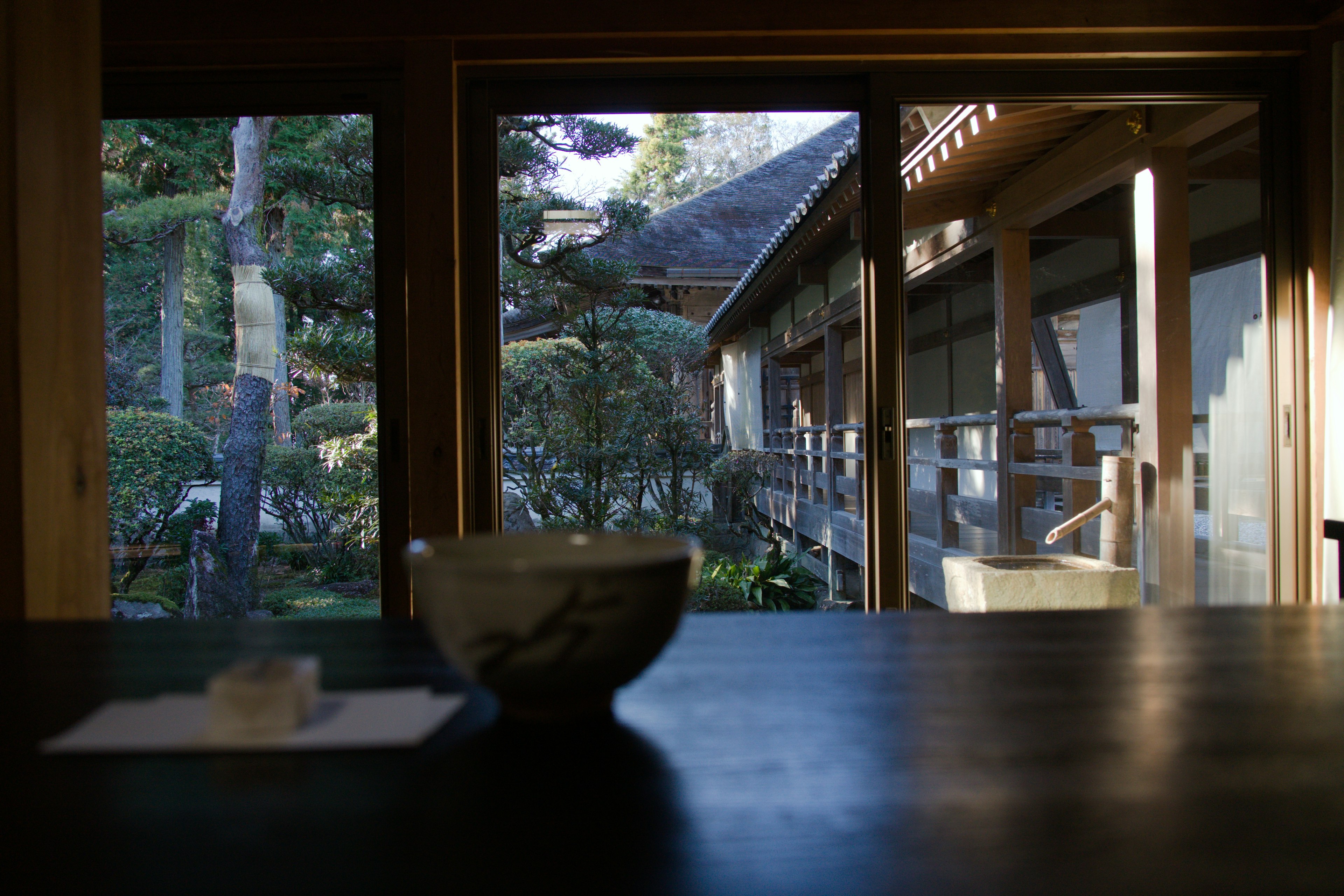 静かな日本の庭を見つめる茶碗と木製のテーブル