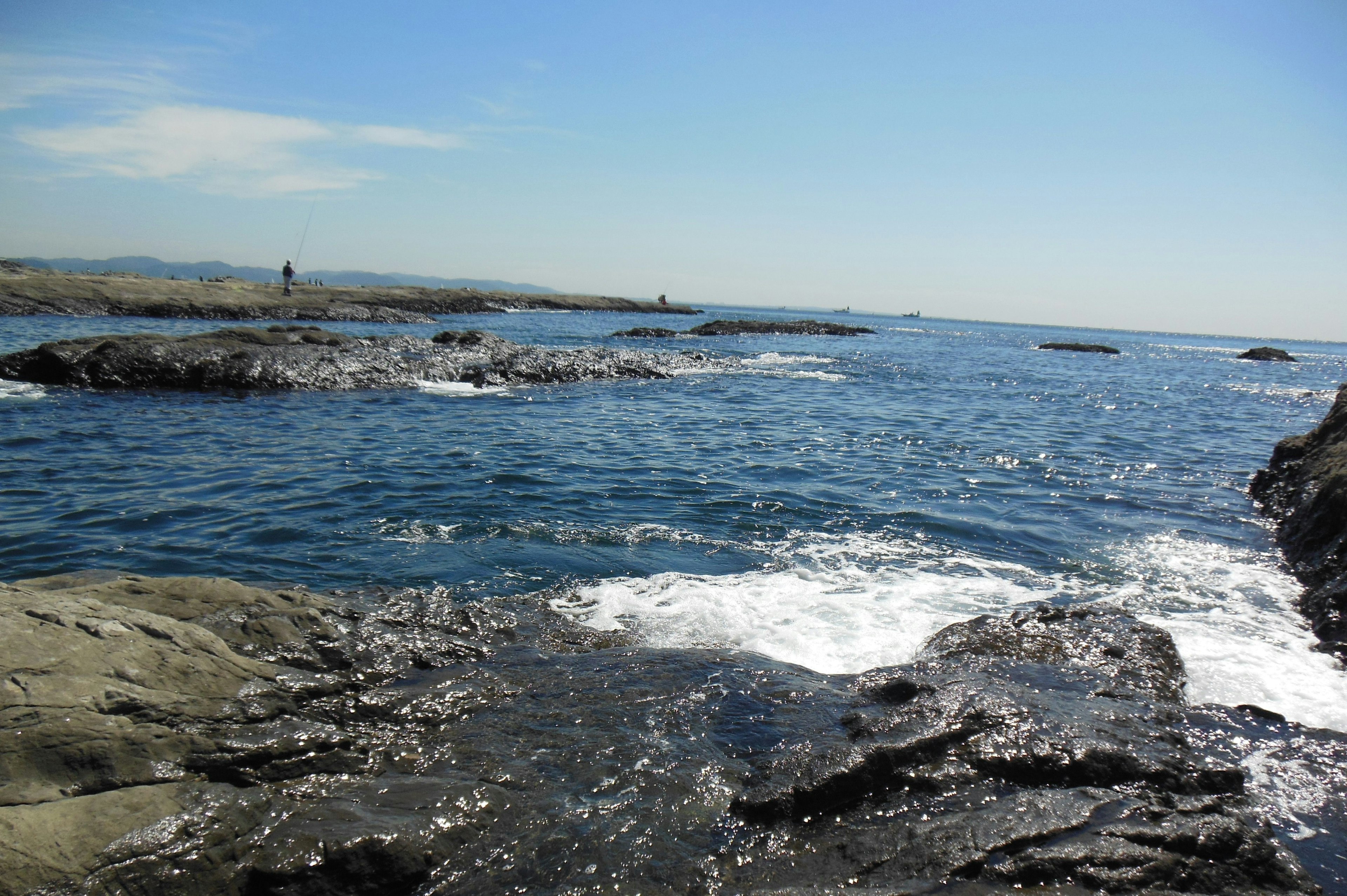 Vista panoramica dell'oceano blu con una costa rocciosa e una figura in lontananza