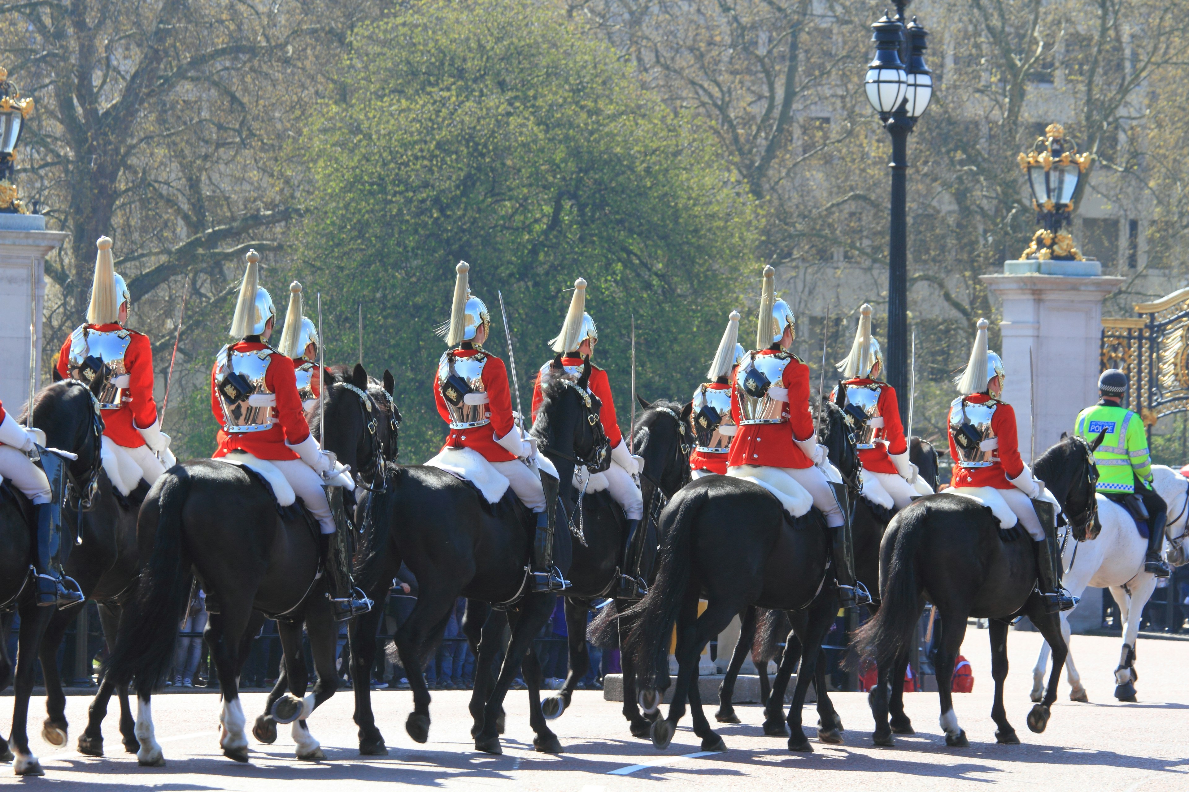 Horse guards in red uniforms riding black horses marching