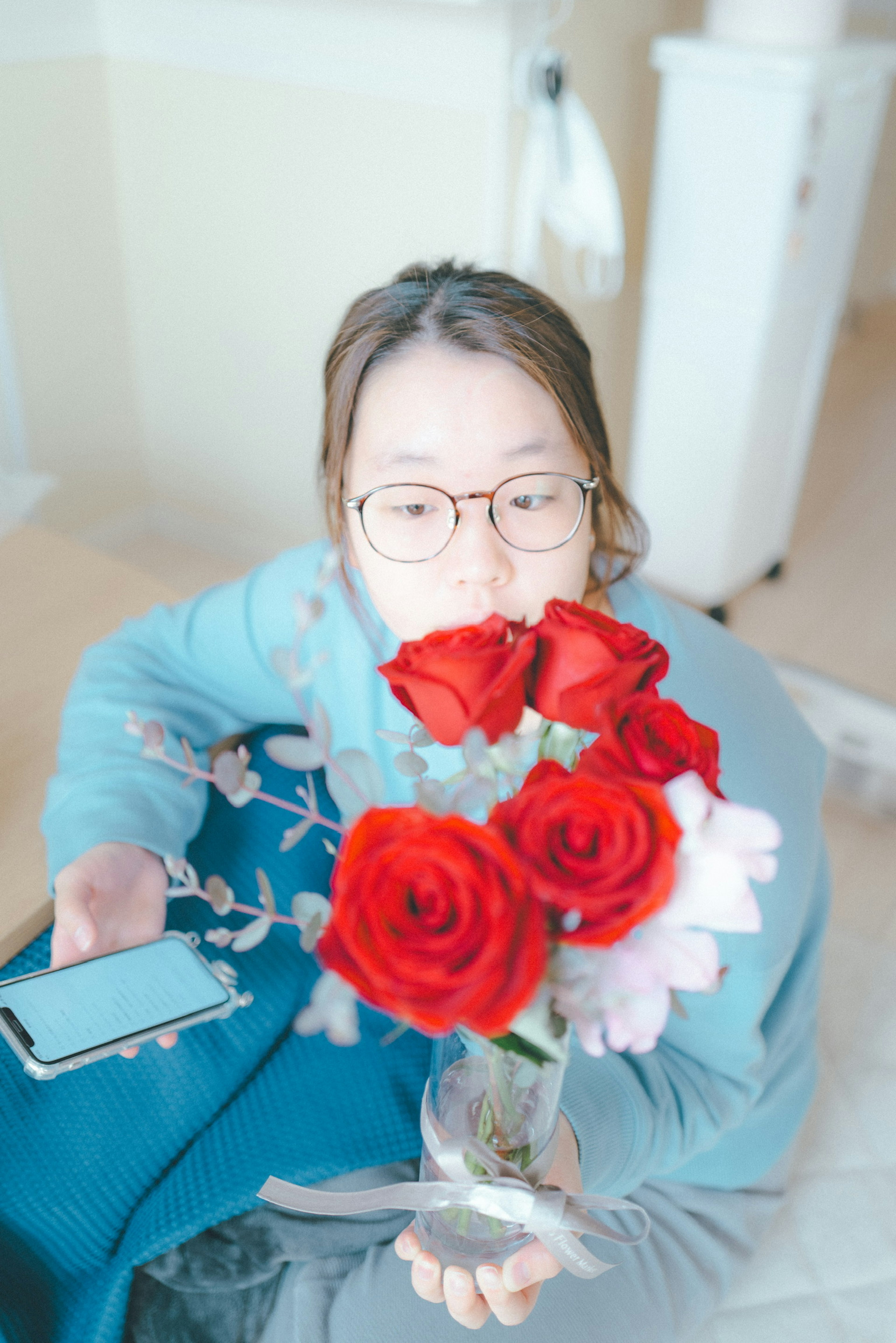 Una mujer sonriendo mientras sostiene un ramo de rosas rojas