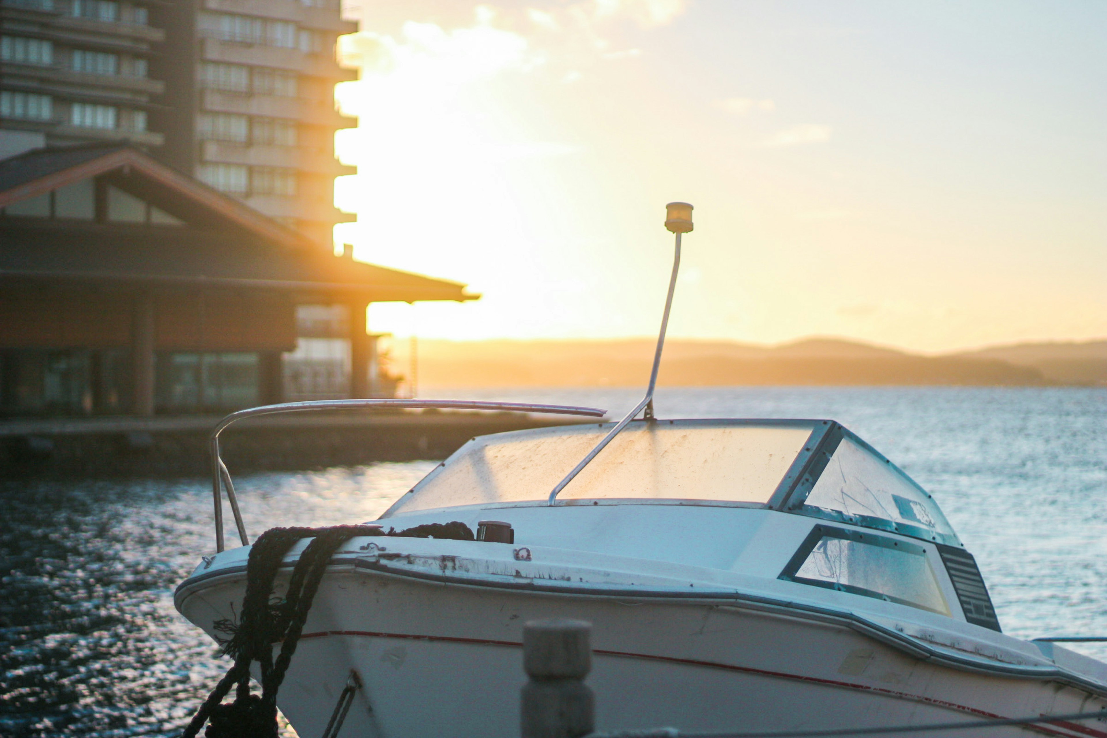 Bateau au coucher du soleil avec bâtiment en bord de mer