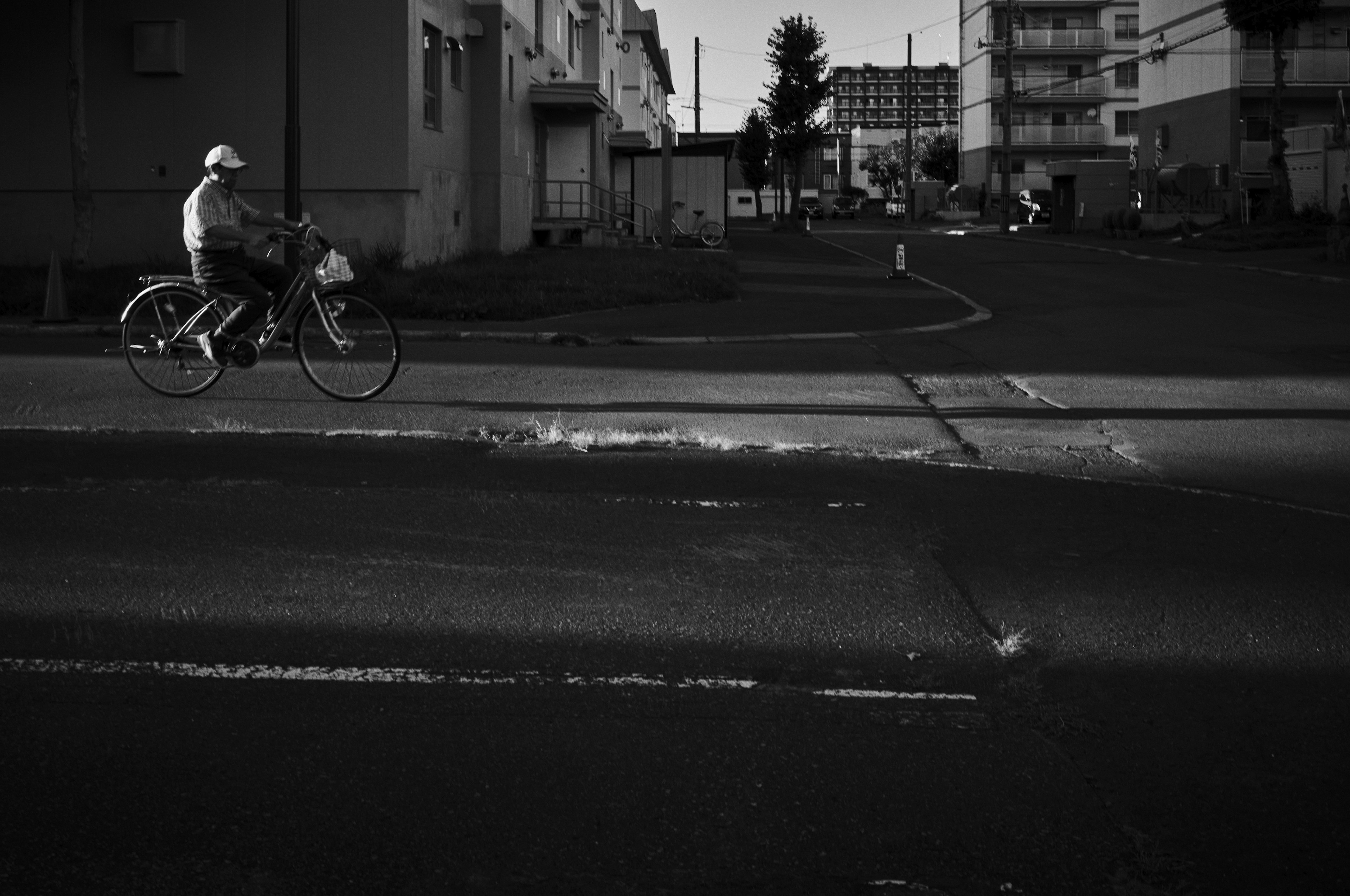 Person riding a bicycle on a street corner in black and white