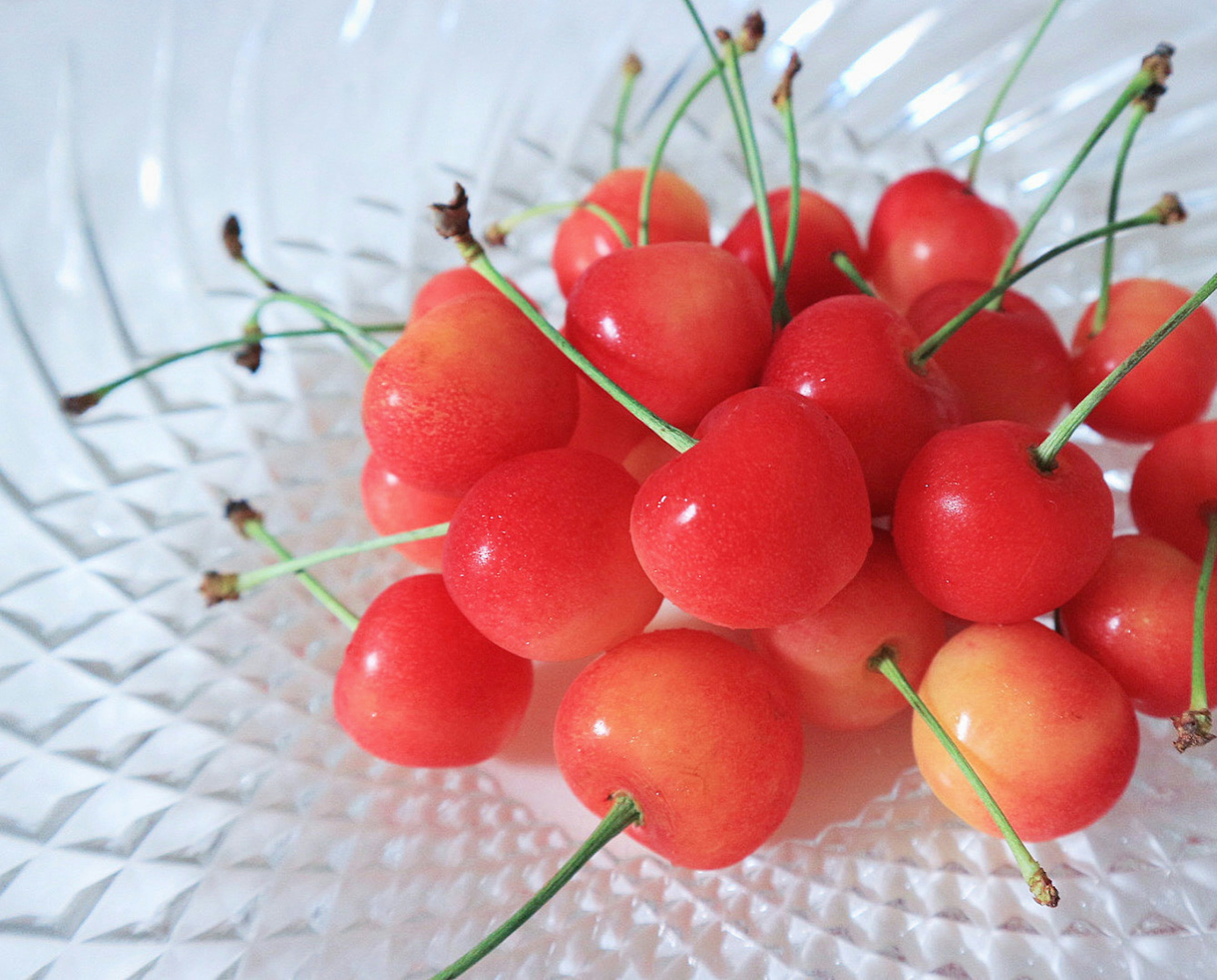 Un grappolo di ciliegie rosse vivaci disposte in una ciotola di vetro trasparente