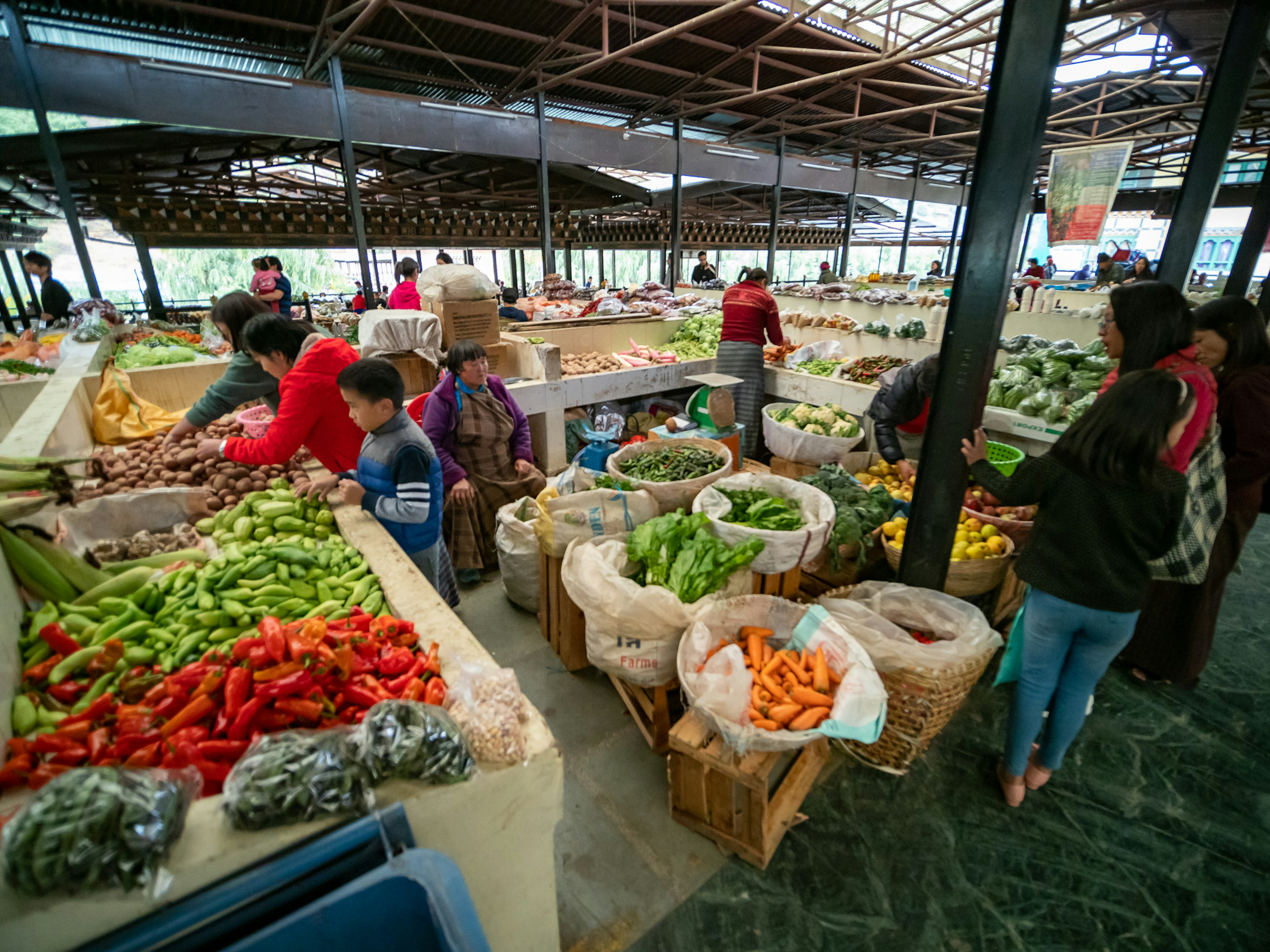 市場で新鮮な野菜を販売する人々と買い物客の風景