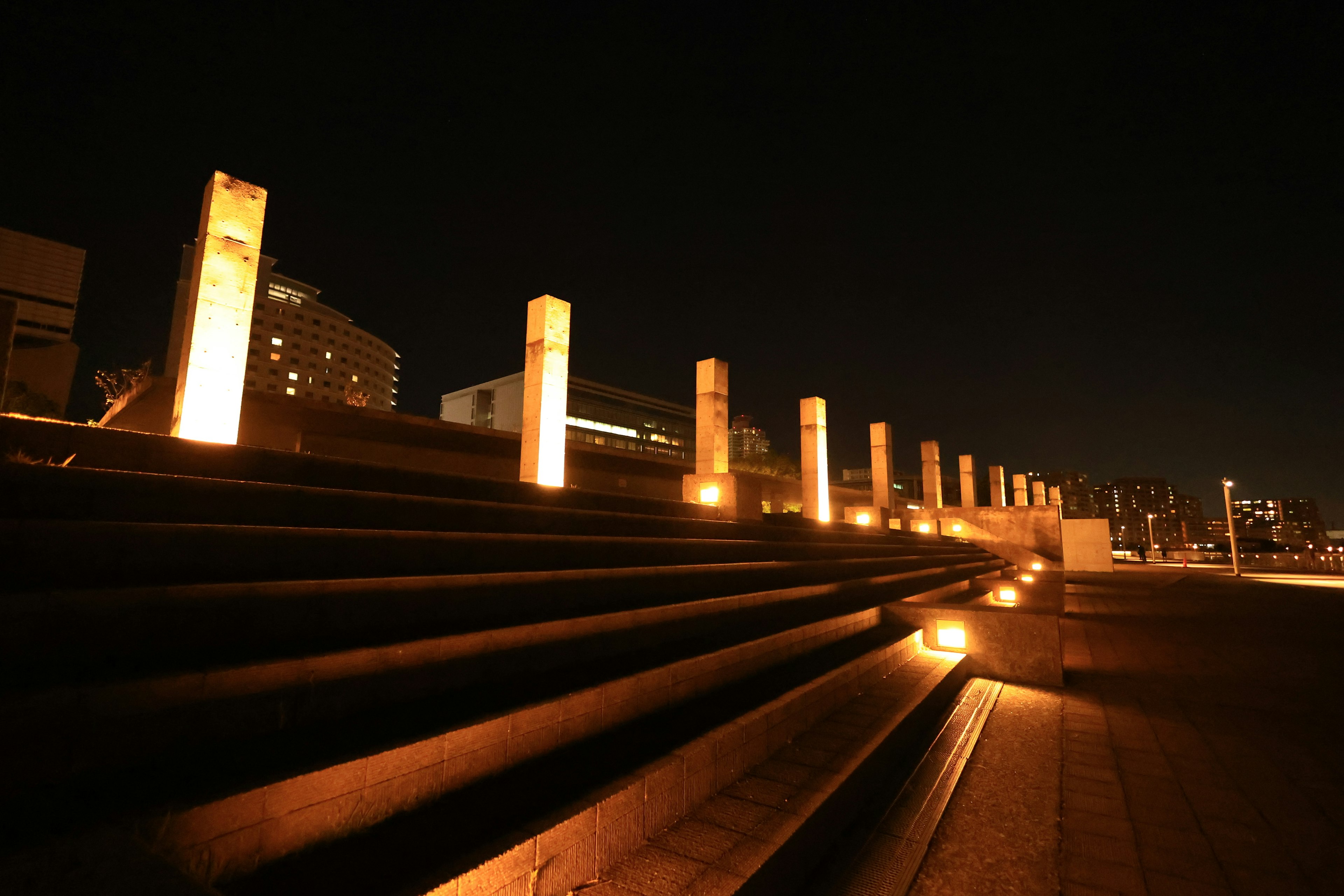 Pilares de concreto iluminados a lo largo de una escalera por la noche