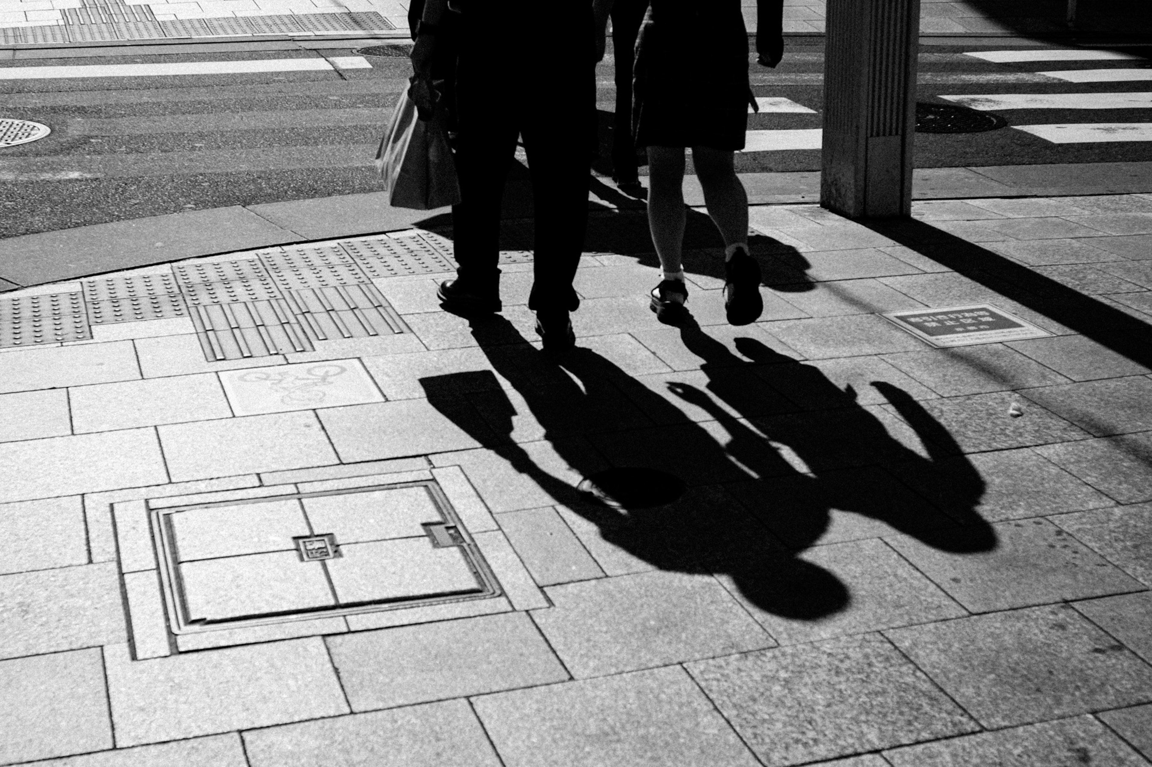 Silhouettes de personnes traversant une rue en noir et blanc