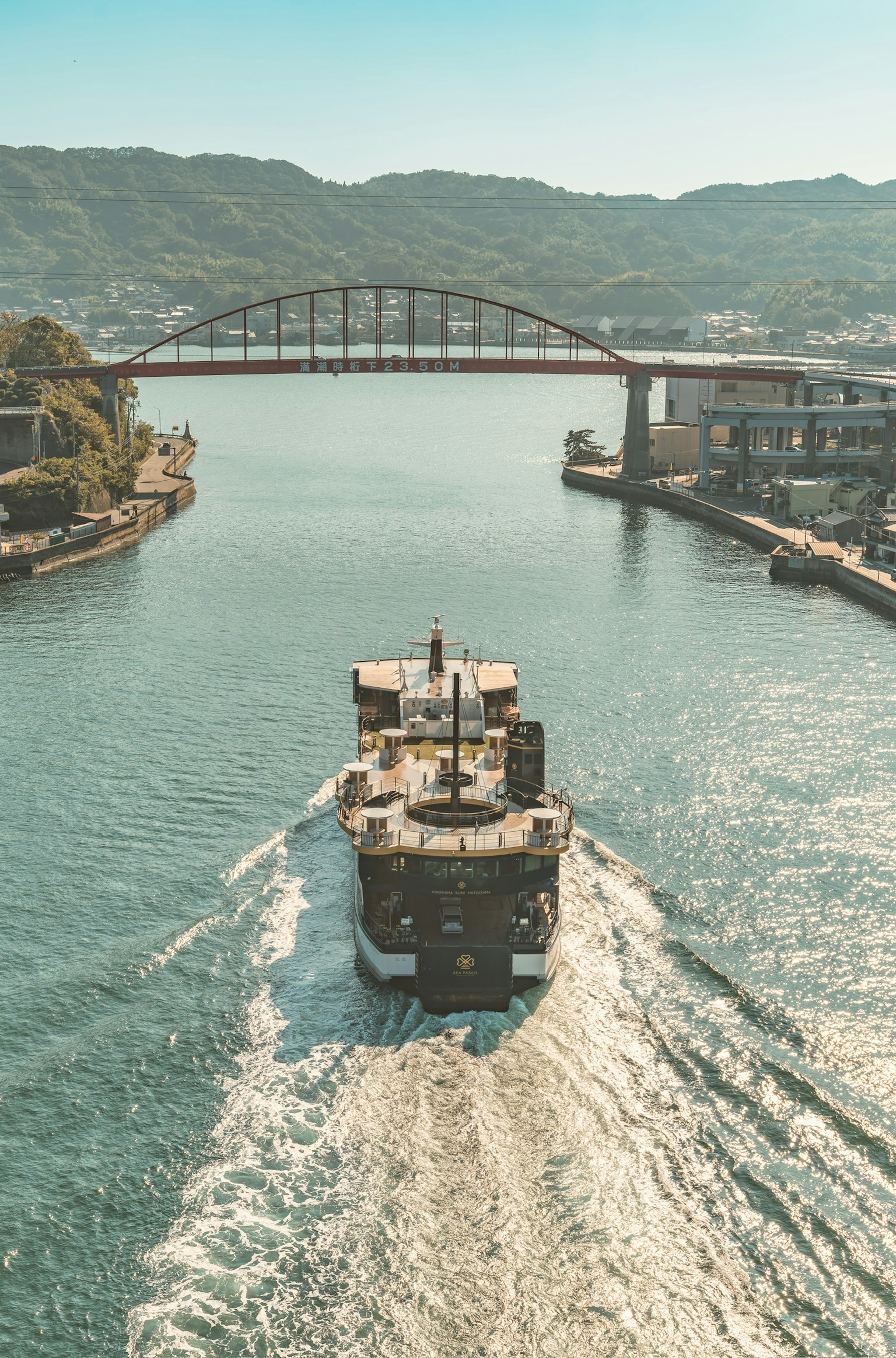 Cargo ship navigating a river with a bridge in the background